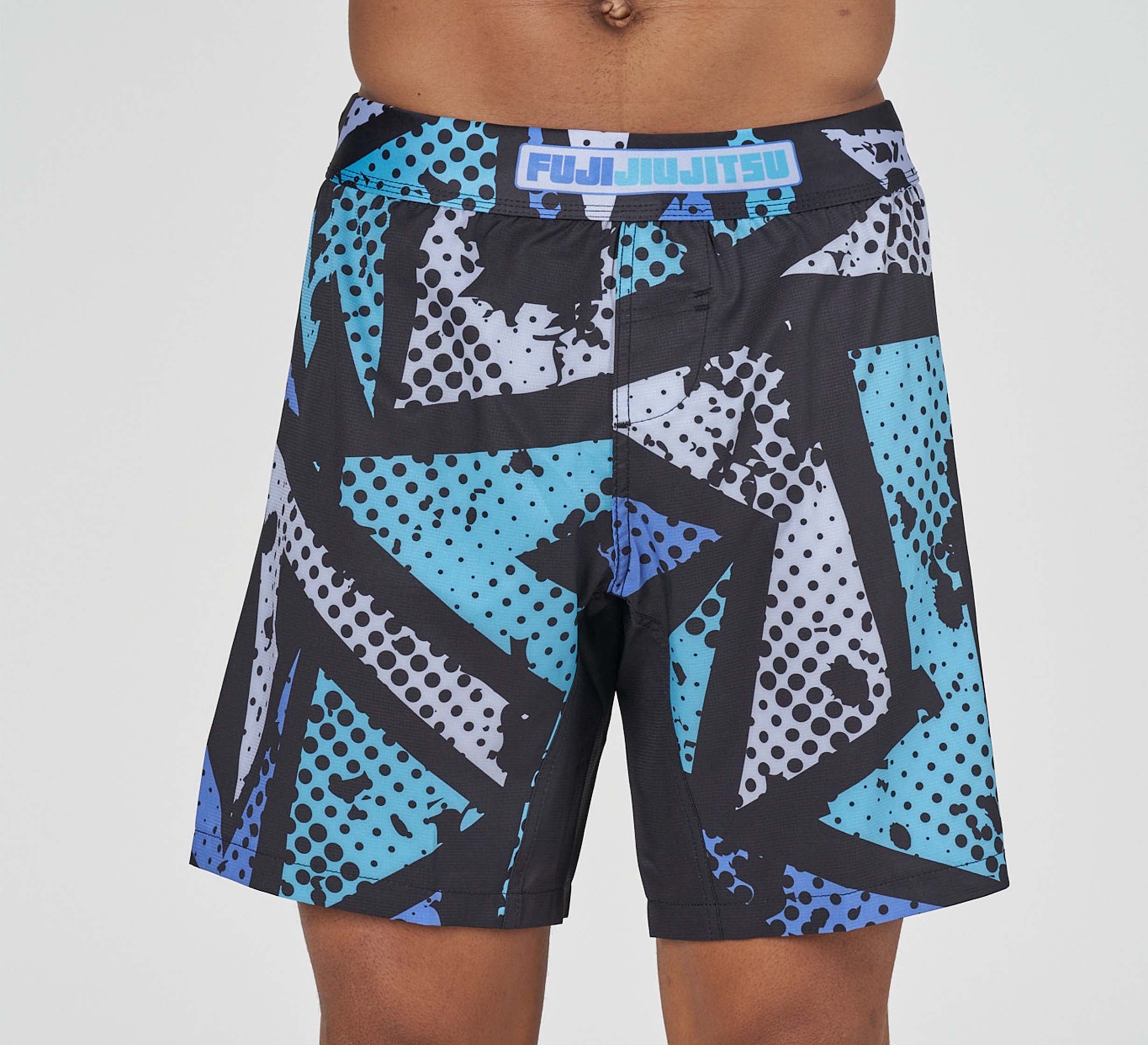 A person wearing Shuriken Flex Lite Shorts Blue/Purple, featuring a bold black, blue, and white geometric pattern and FUJI JIUJITSU on the waistband.