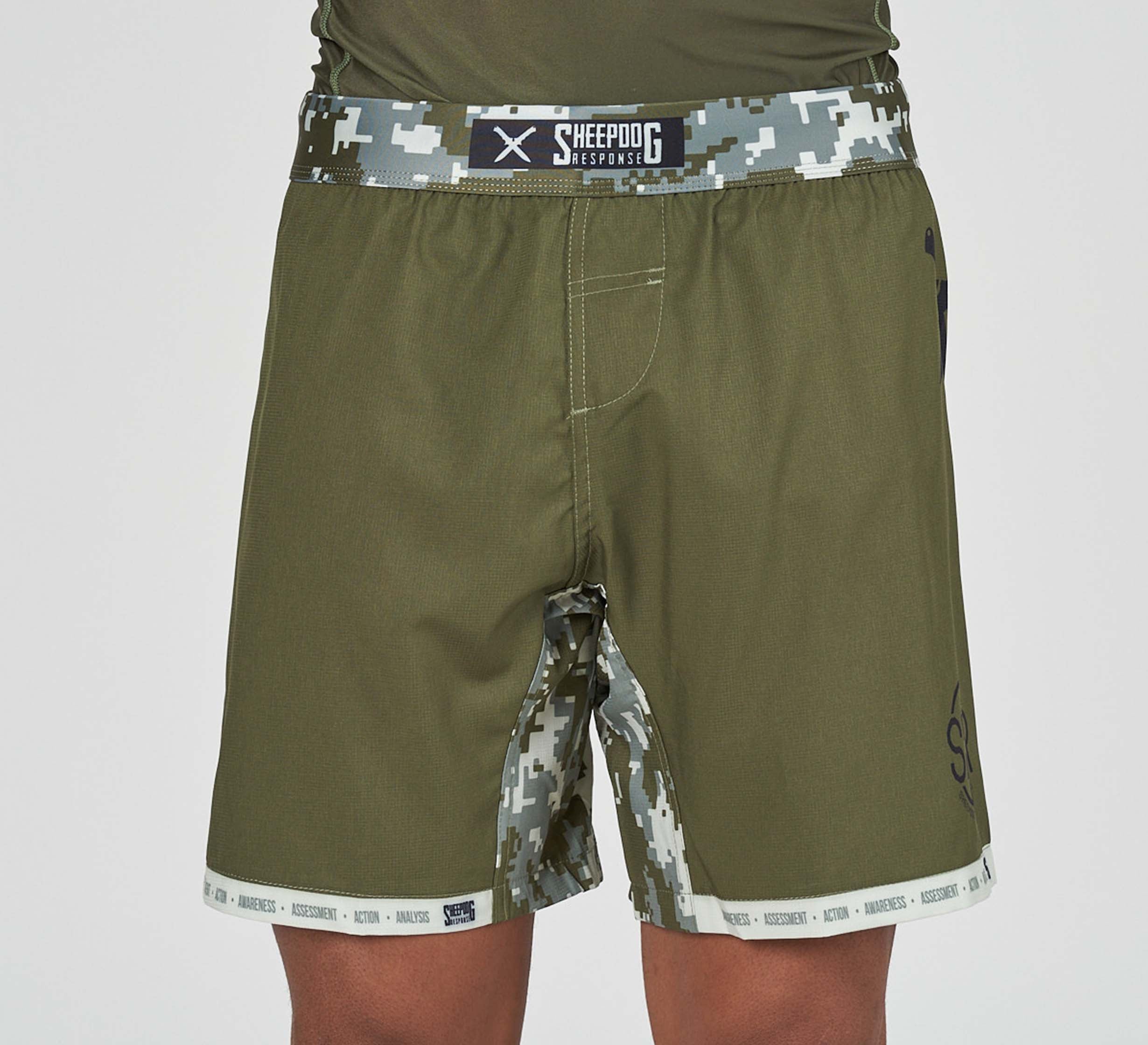A person wears Sheepdog Response Flex Lite Shorts in Military Green, featuring a digital camo waistband and trim with "Sheepdog" branding, shown waist to mid-thigh against a plain background.