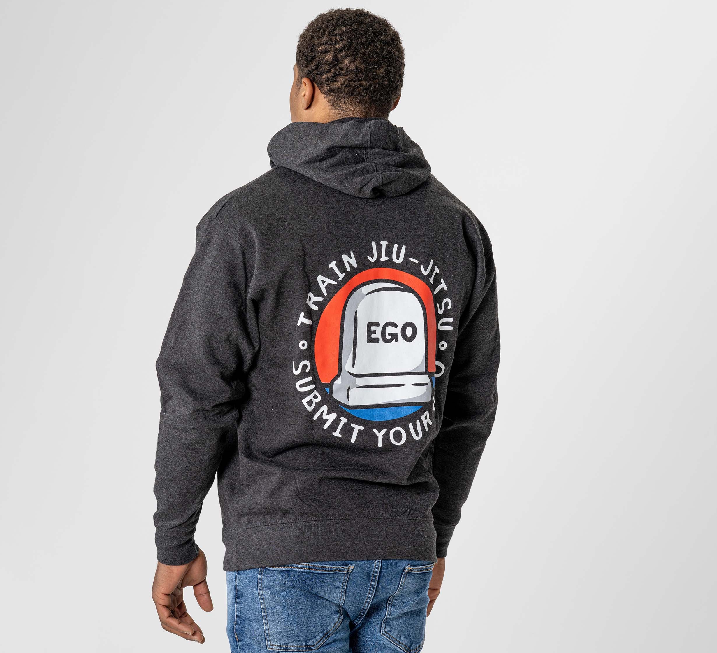 Someone wears the Submit Your Ego Hoodie in heather black, which features a jiu-jitsu belt graphic and the word "EGO" in the center, surrounded by the phrase “Train Jiu-Jitsu, Submit Your Ego” on the back.