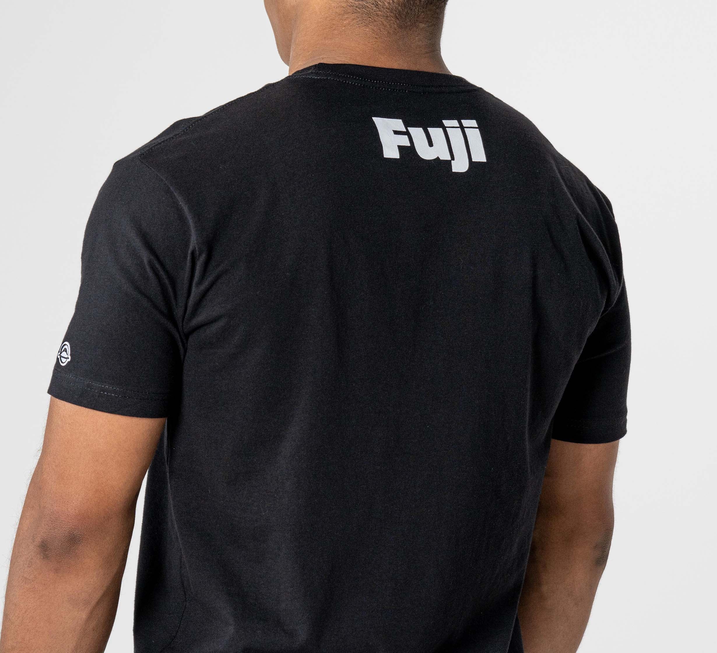A person wearing the Jiu Jitsu Player T-Shirt Black with "Fuji" printed in white on the upper back, standing against a plain light background.
