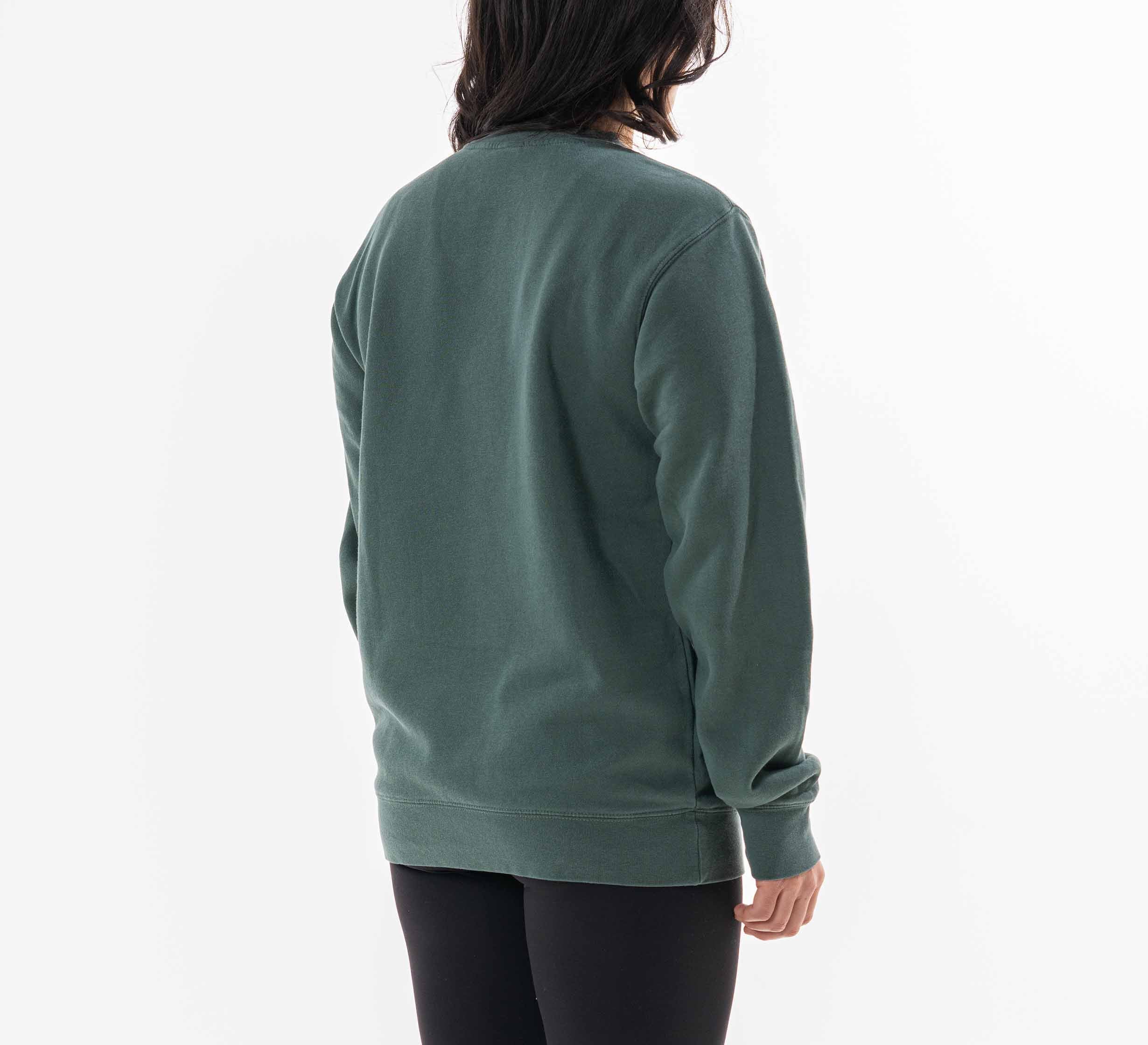 A woman with shoulder-length dark hair is seen from the back, wearing the Womens Signature Crewneck Green sweatshirt and black pants, standing against a plain white background.