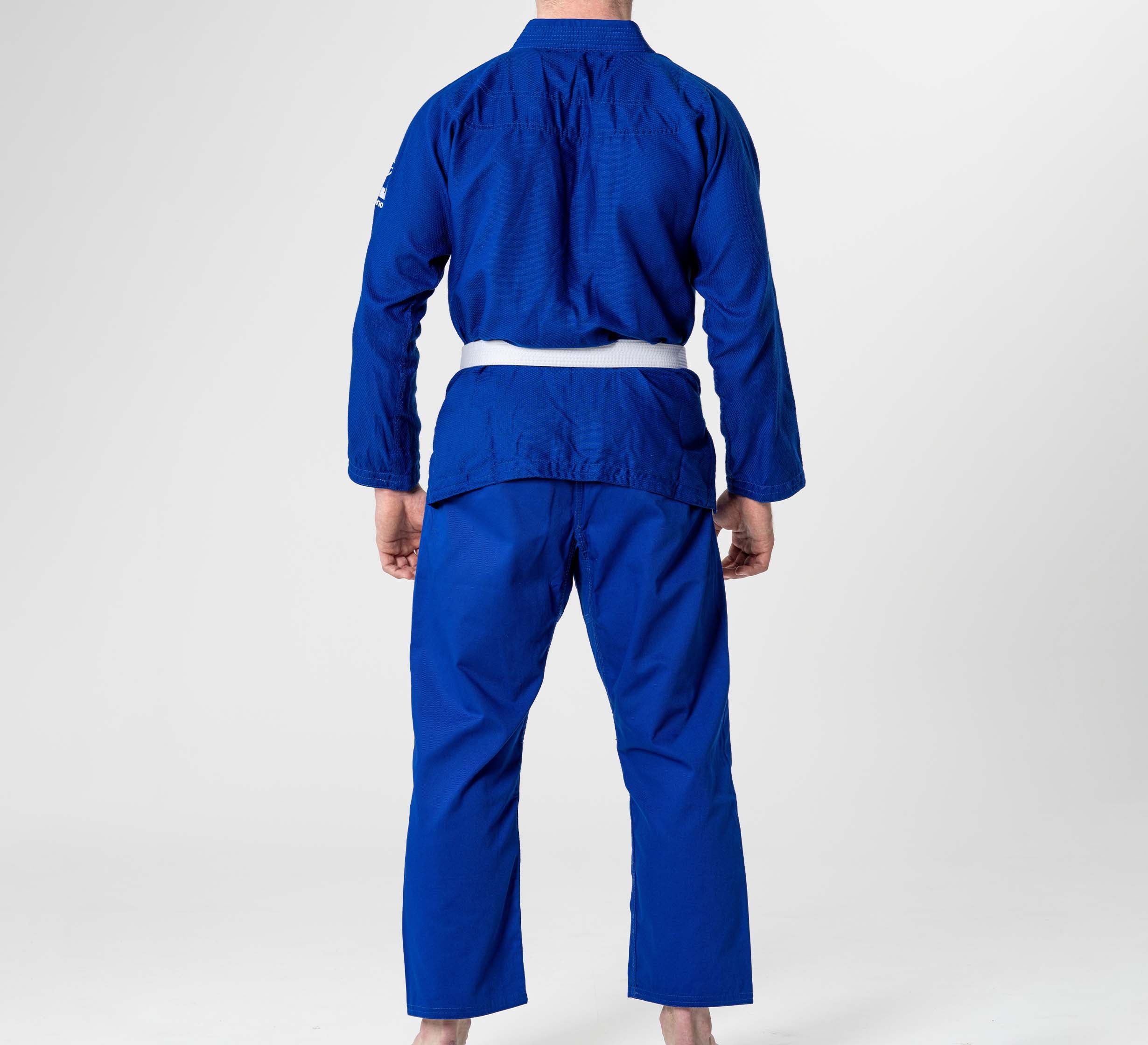 A person stands barefoot on a white background, facing away from the camera, wearing the Starter Adult BJJ Gi Blue with a white belt.