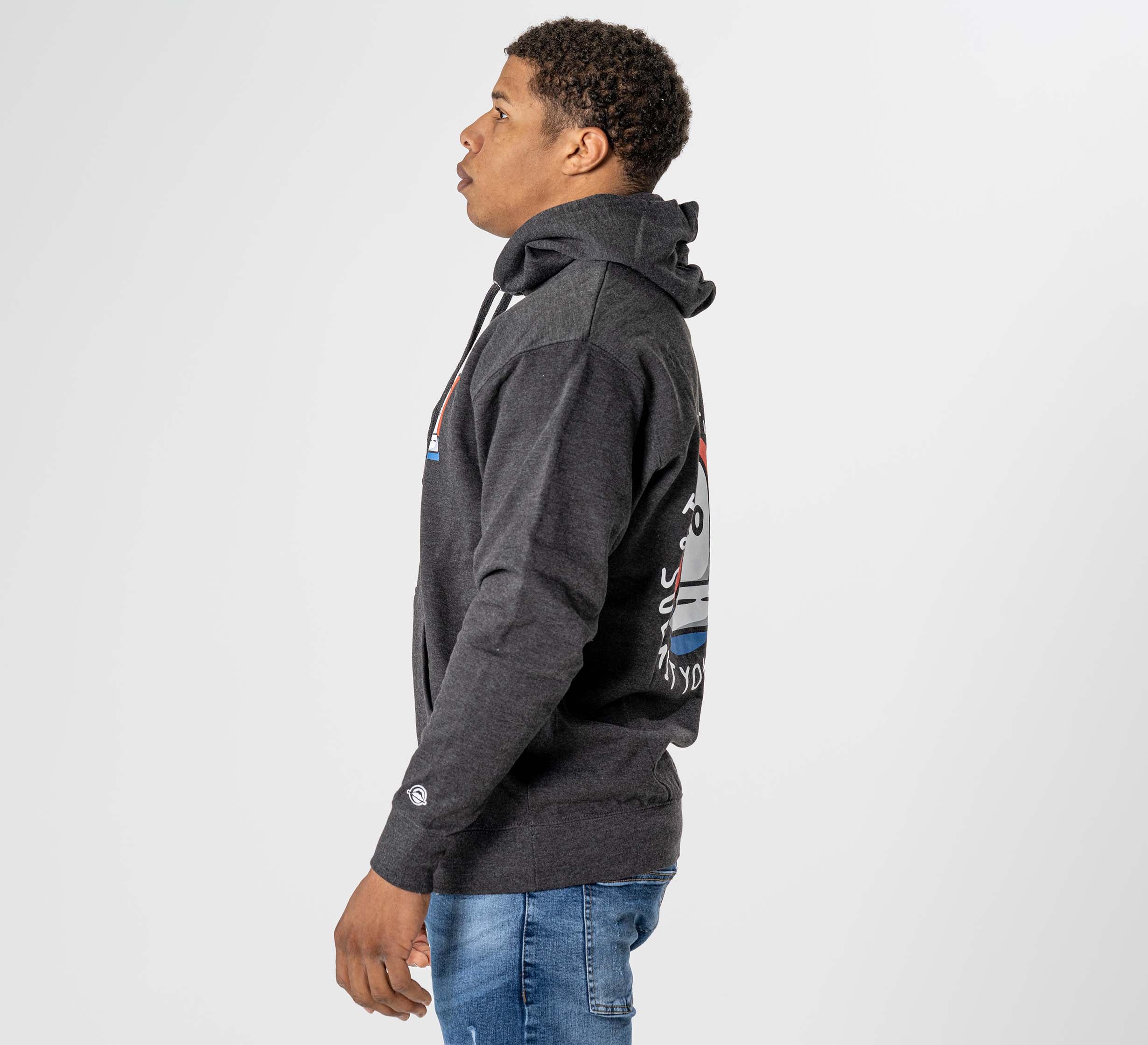 A man wearing the Submit Your Ego Hoodie in Heather Black and blue jeans stands sideways against a plain white background, gazing upward with lips slightly parted.