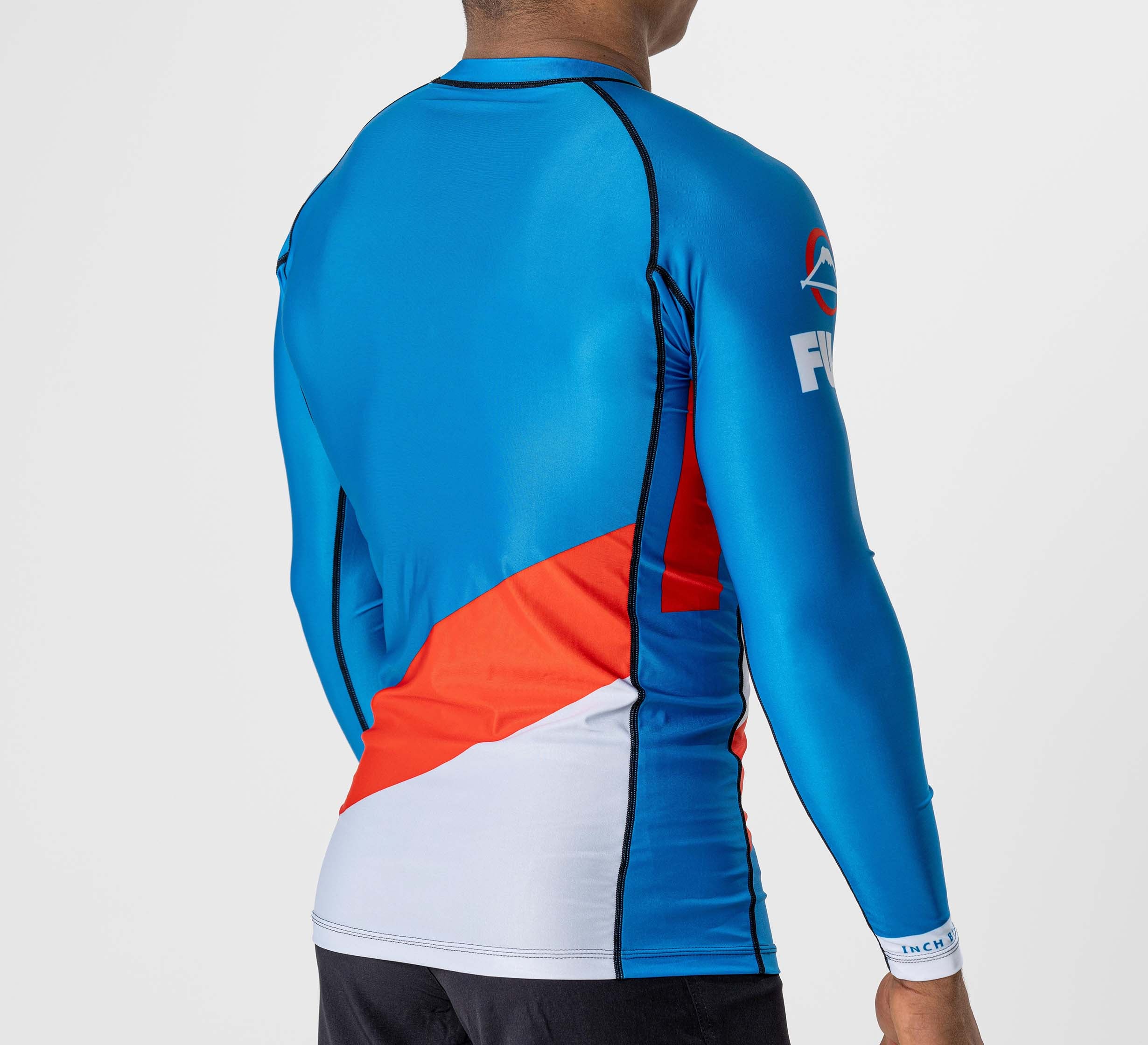 A person is shown from the back wearing the Pacer Flex Lite Long Sleeve Rashguard Blue/Red, featuring black seam lines and a logo on the left arm, against a plain light background.
