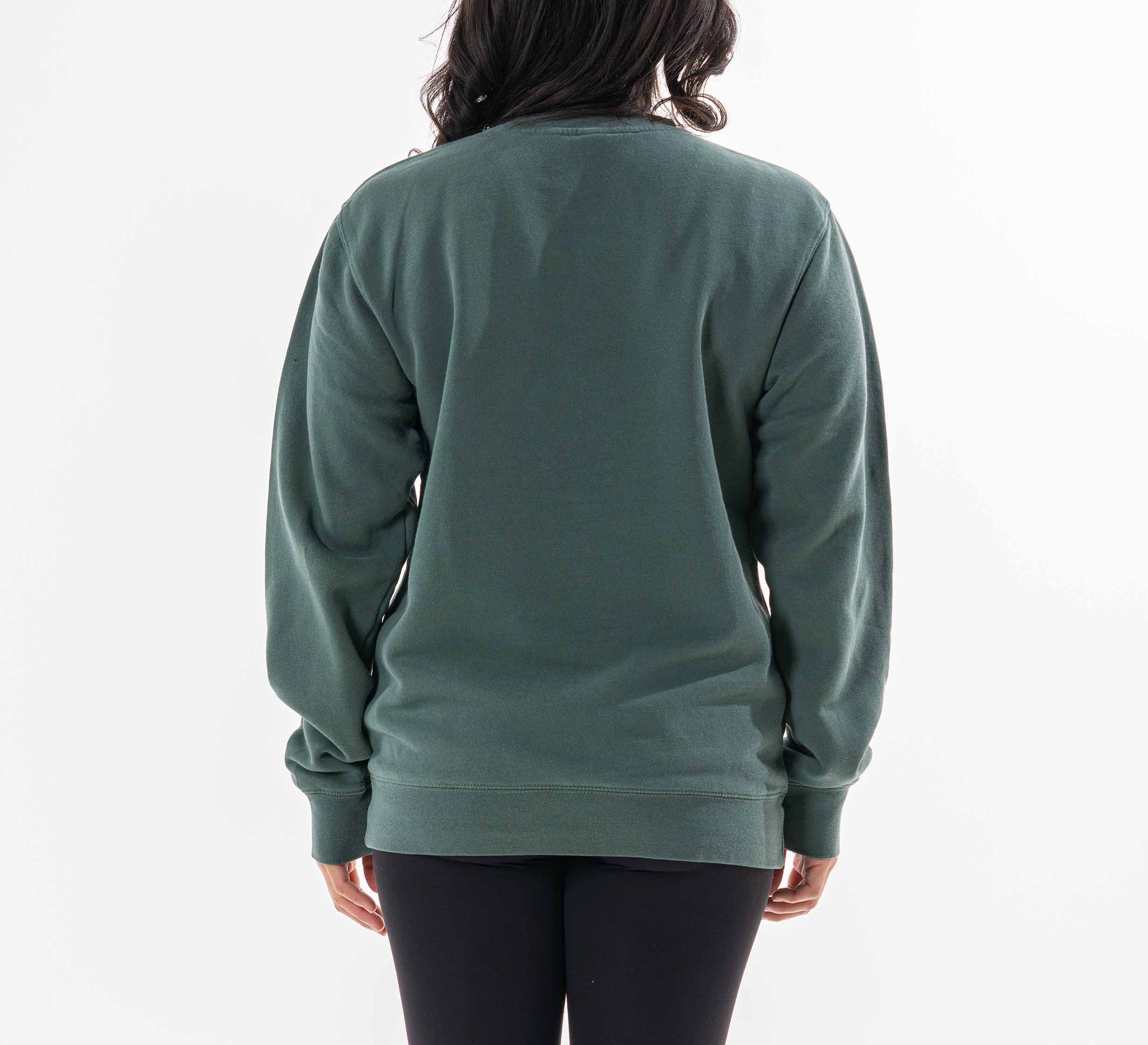 A woman with long, dark hair stands with her back to the camera against a plain white background, modeling the Womens Signature Crewneck Green sweatshirt with black pants.