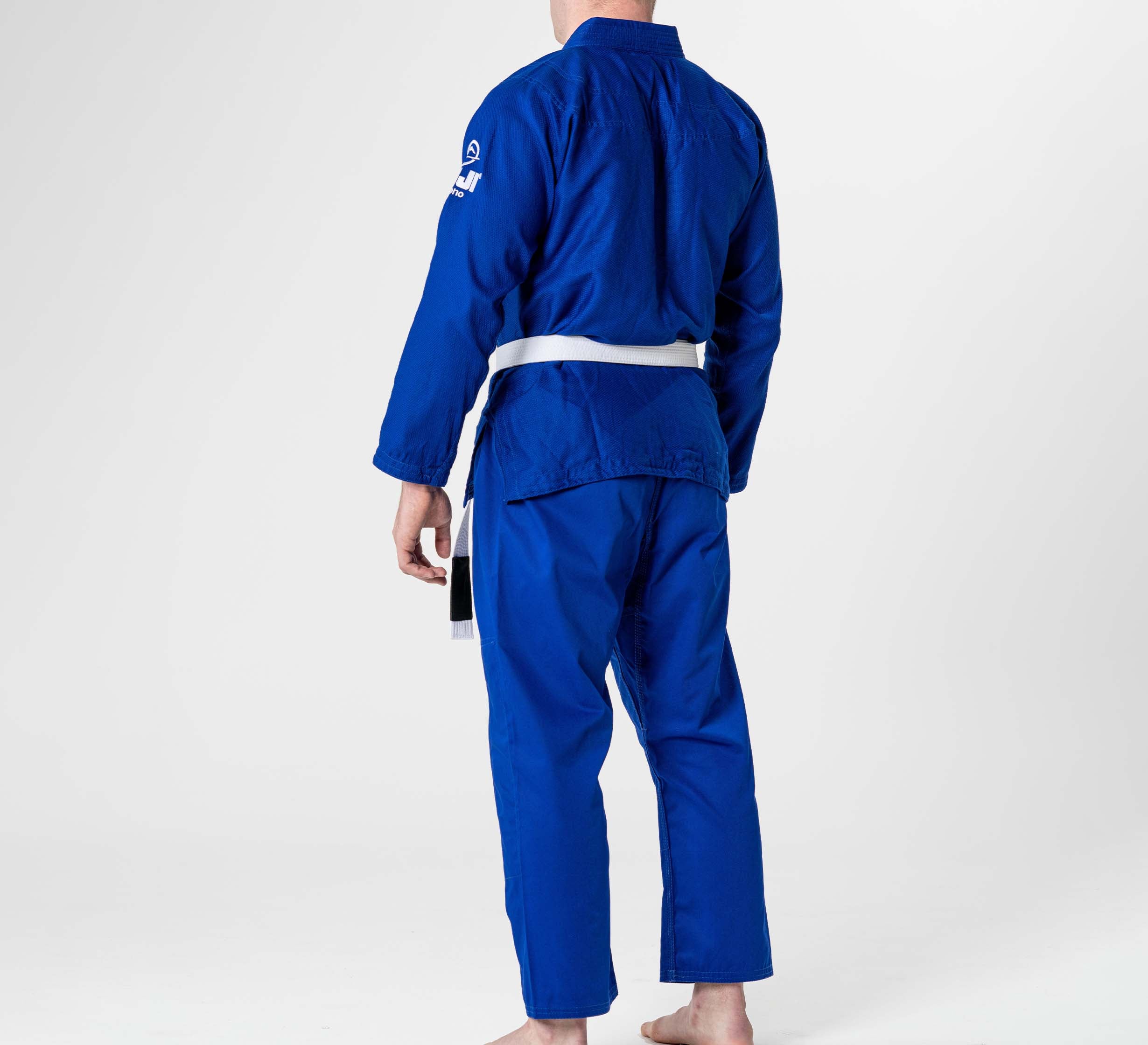 A person stands barefoot and facing away in a plain white space, wearing a Starter Adult BJJ Gi Blue with a white belt.