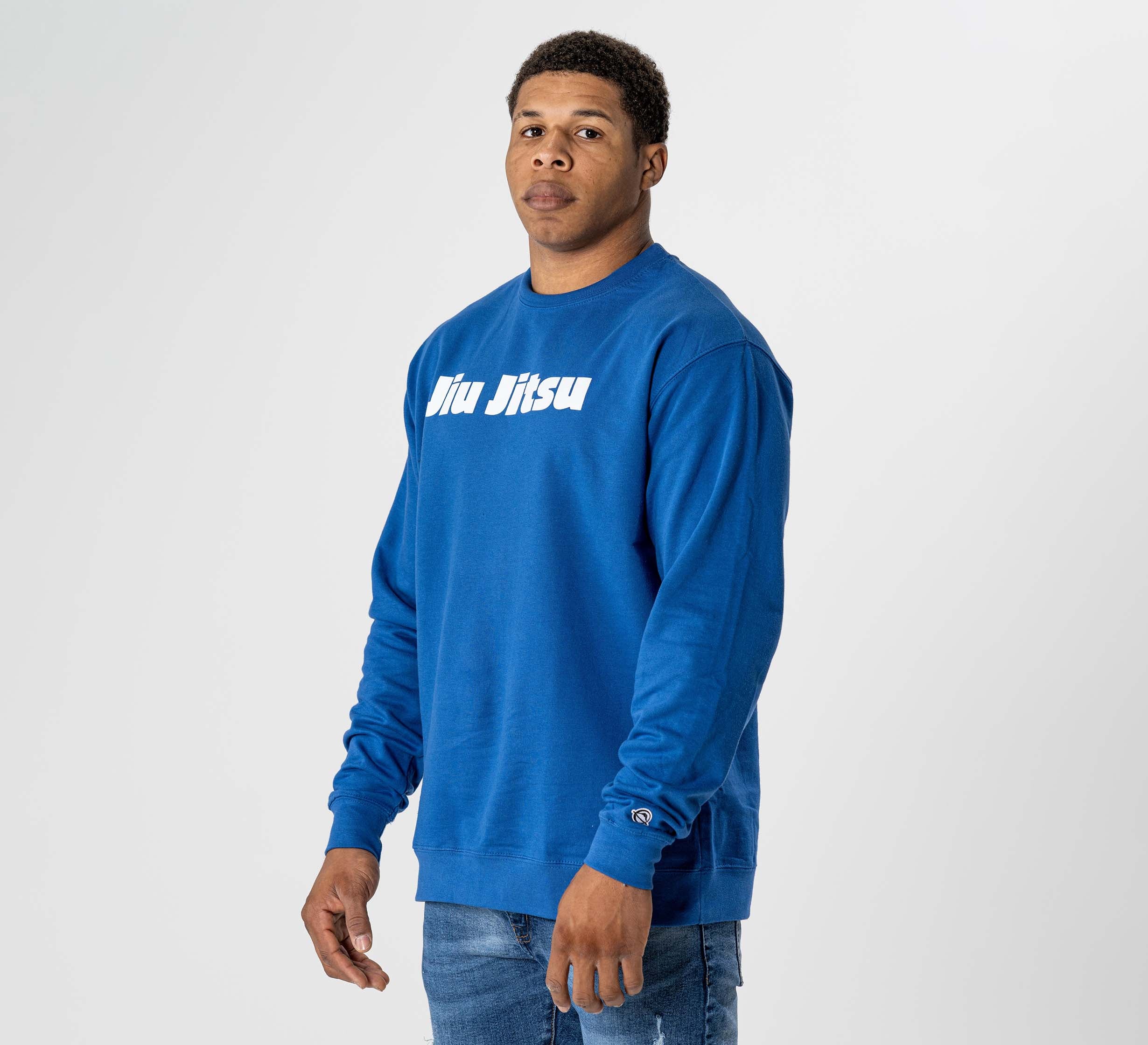 Someone wearing the Jiu Jitsu Player Crewneck Blue, featuring "jiu jitsu" in white text on the front, stands against a plain light background.
