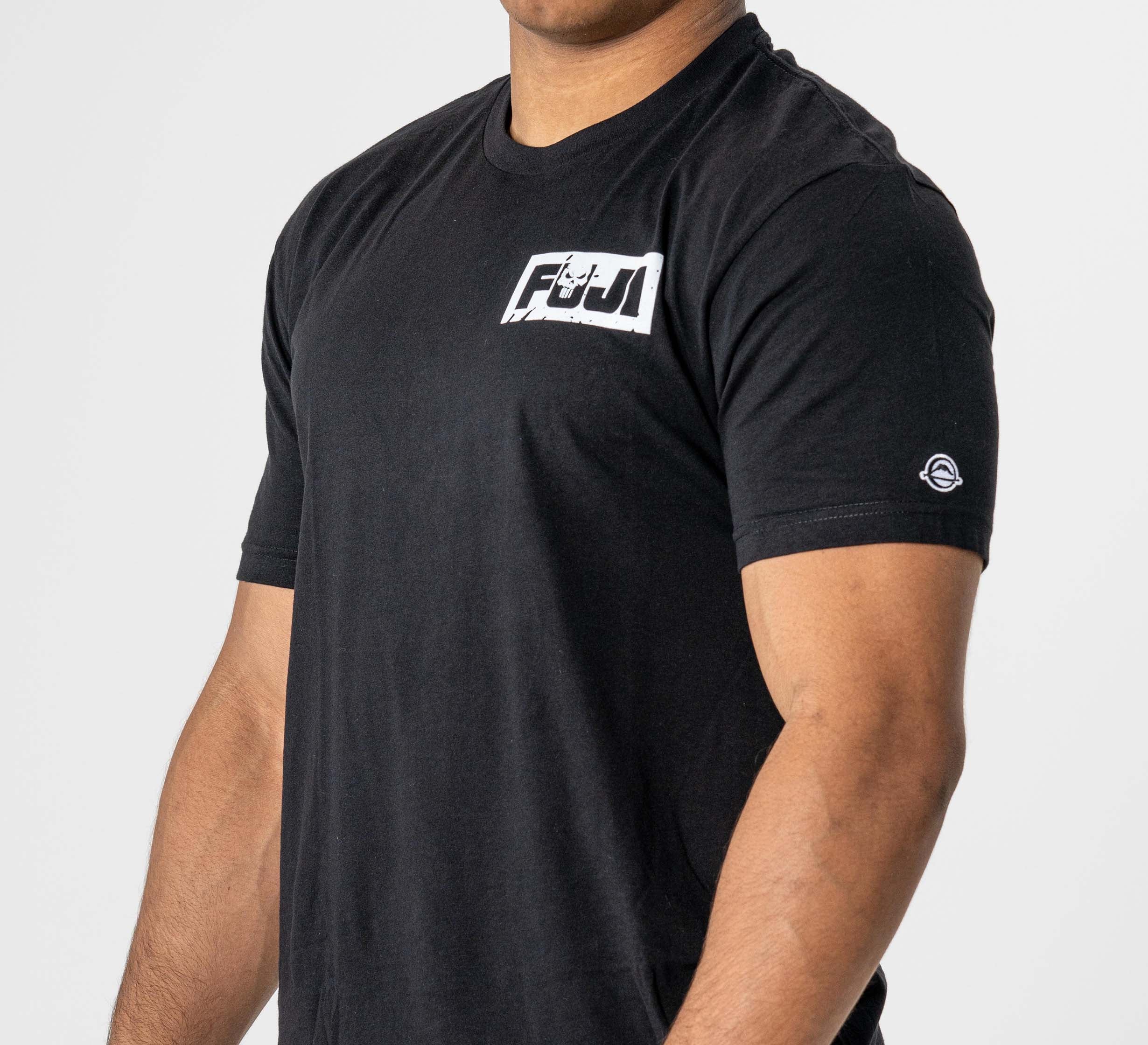 A person wearing the Punishment T-Shirt Black, featuring a white FIJI logo on the left chest and a small circular emblem on the left sleeve, stands against a plain light background.