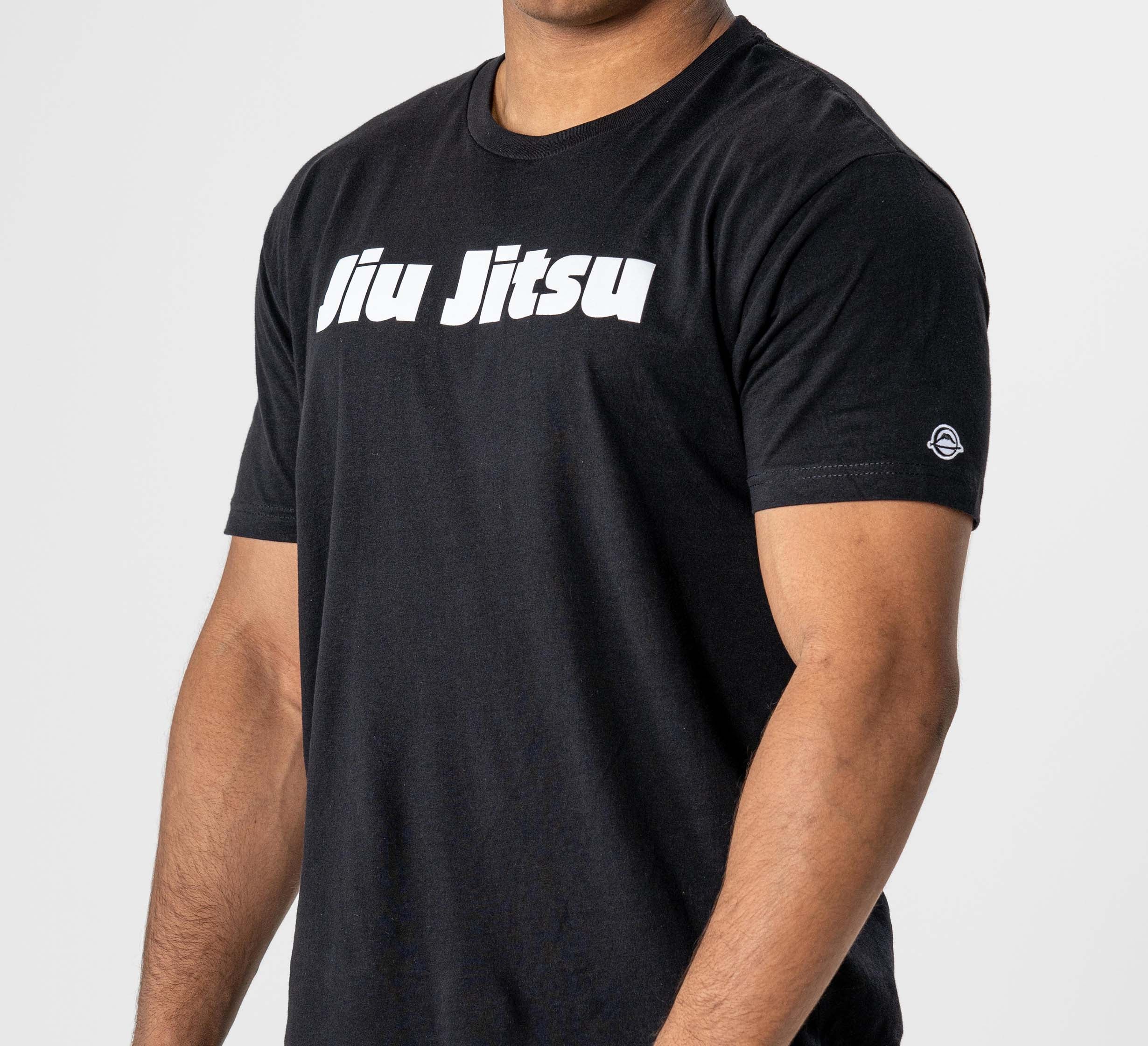 Someone wearing the Jiu Jitsu Player T-Shirt Black, featuring bold white "Jiu Jitsu" lettering across the chest, stands against a plain light background.