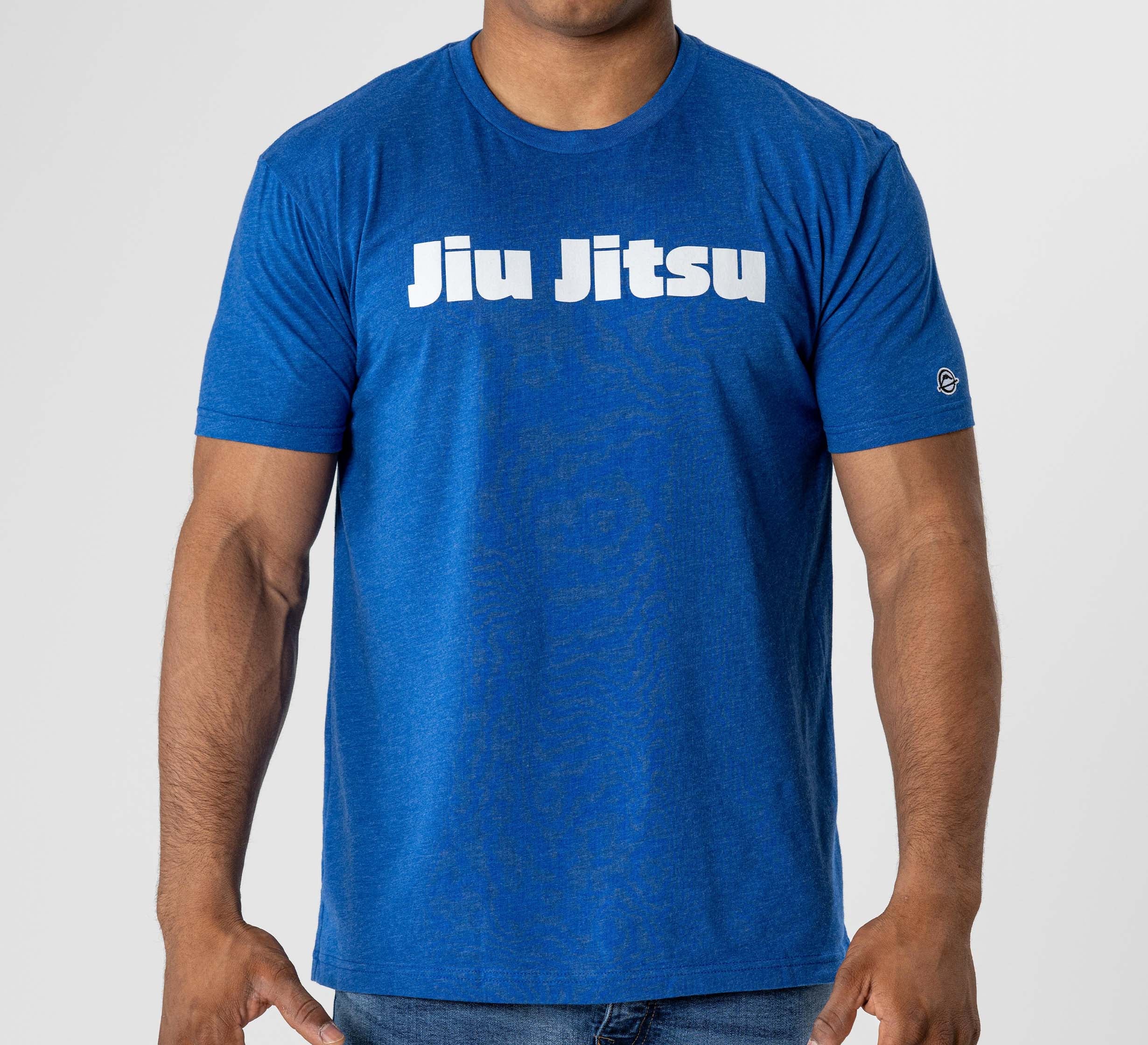 A person wearing the Jiu Jitsu Player T-Shirt Blue, featuring bold white "Jiu Jitsu" lettering on the chest, stands against a plain light background.