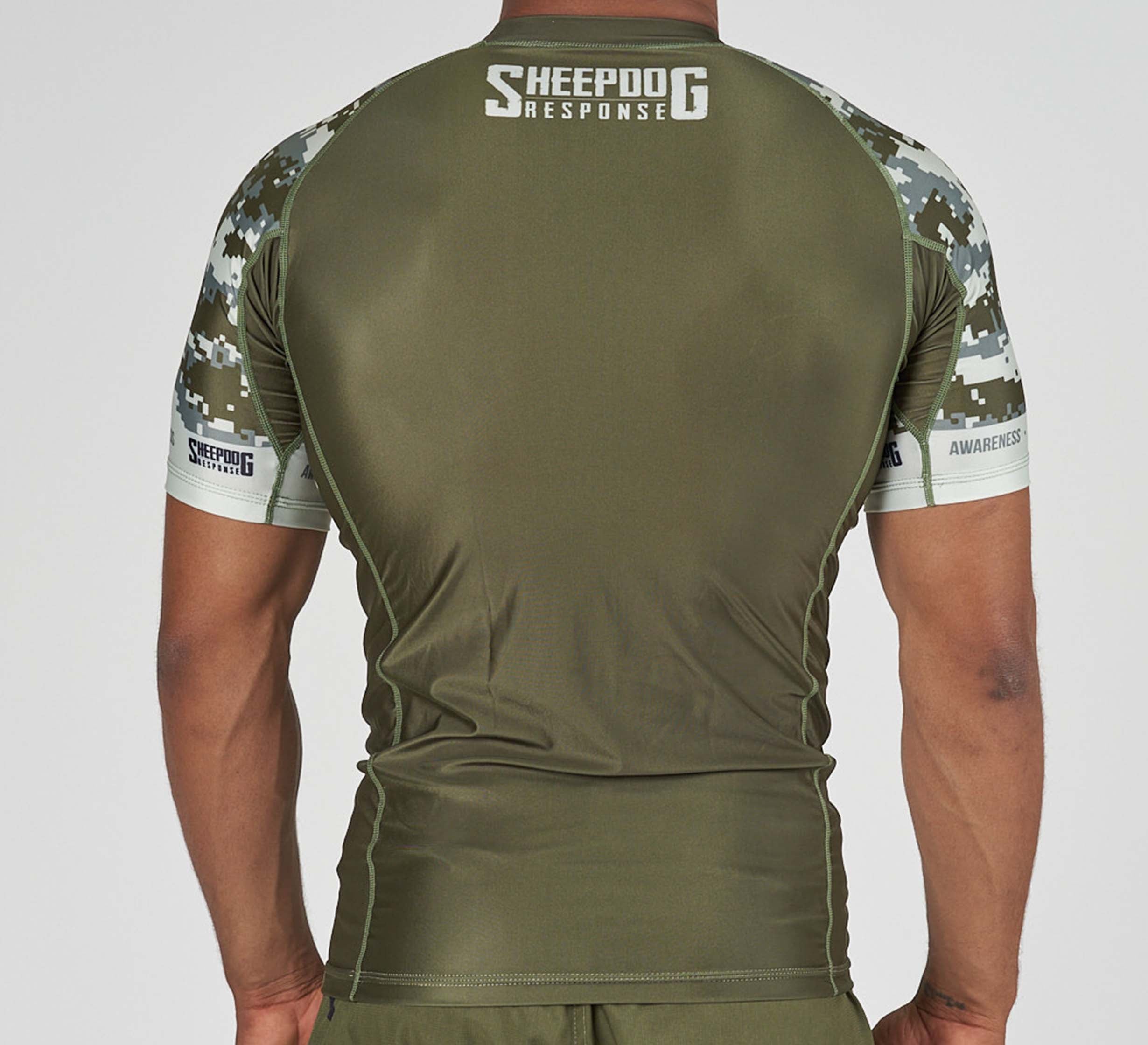 A person seen from behind wears the Sheepdog Response Flex Lite Rashguard Military Green, featuring digital camouflage sleeves and "Sheepdog Response" printed on the back.