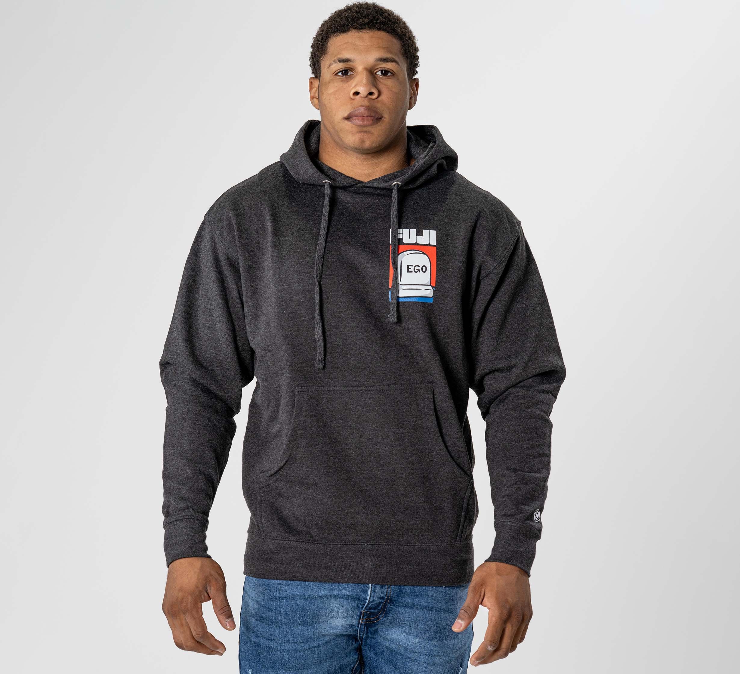 A man wearing the Submit Your Ego Hoodie in Heather Black and blue jeans stands facing forward against a plain light gray background.