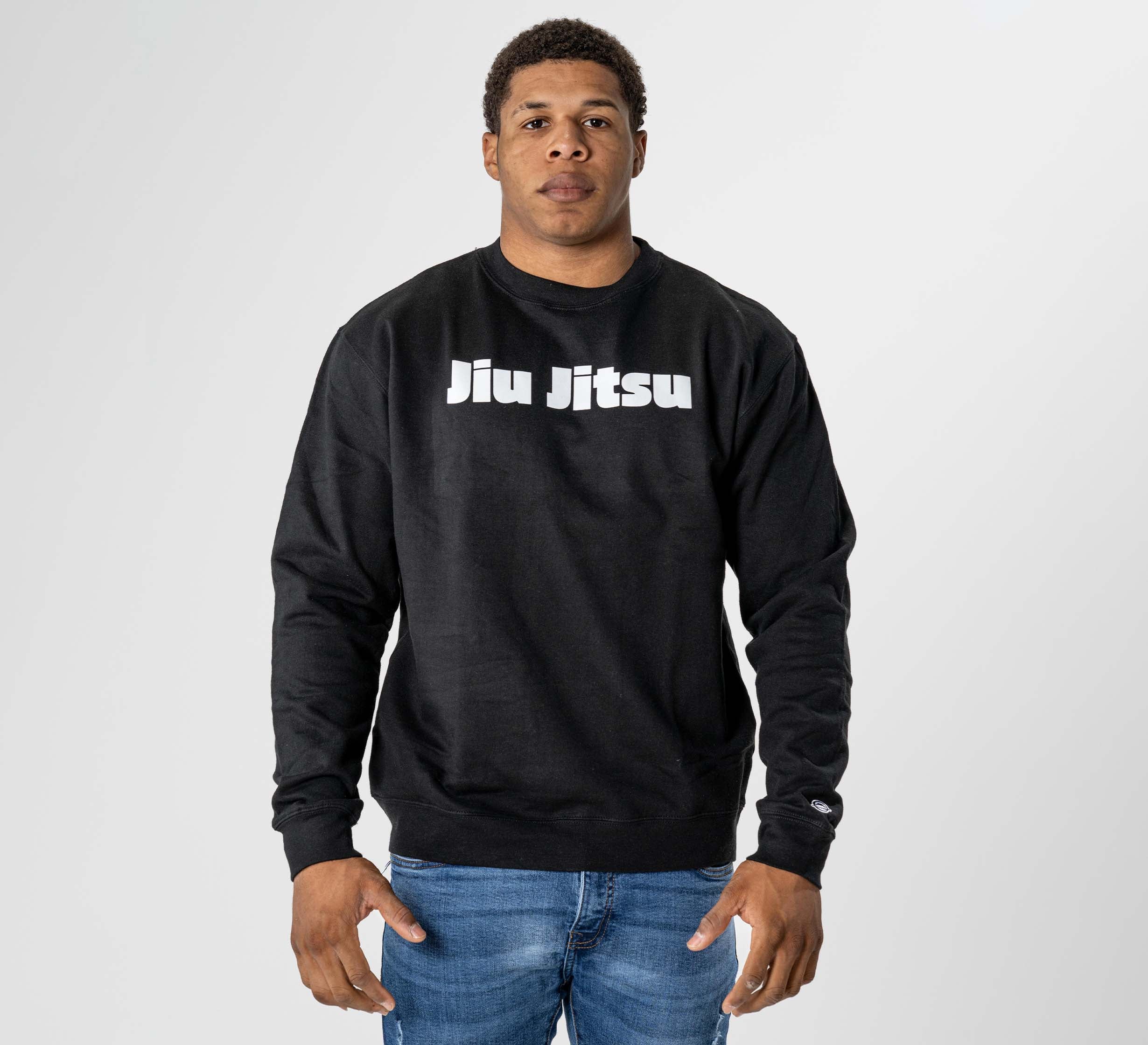 A person models the Jiu Jitsu Player Crewneck Black, featuring bold white "Jiu Jitsu" text, standing against a plain light gray background with arms relaxed at their sides.