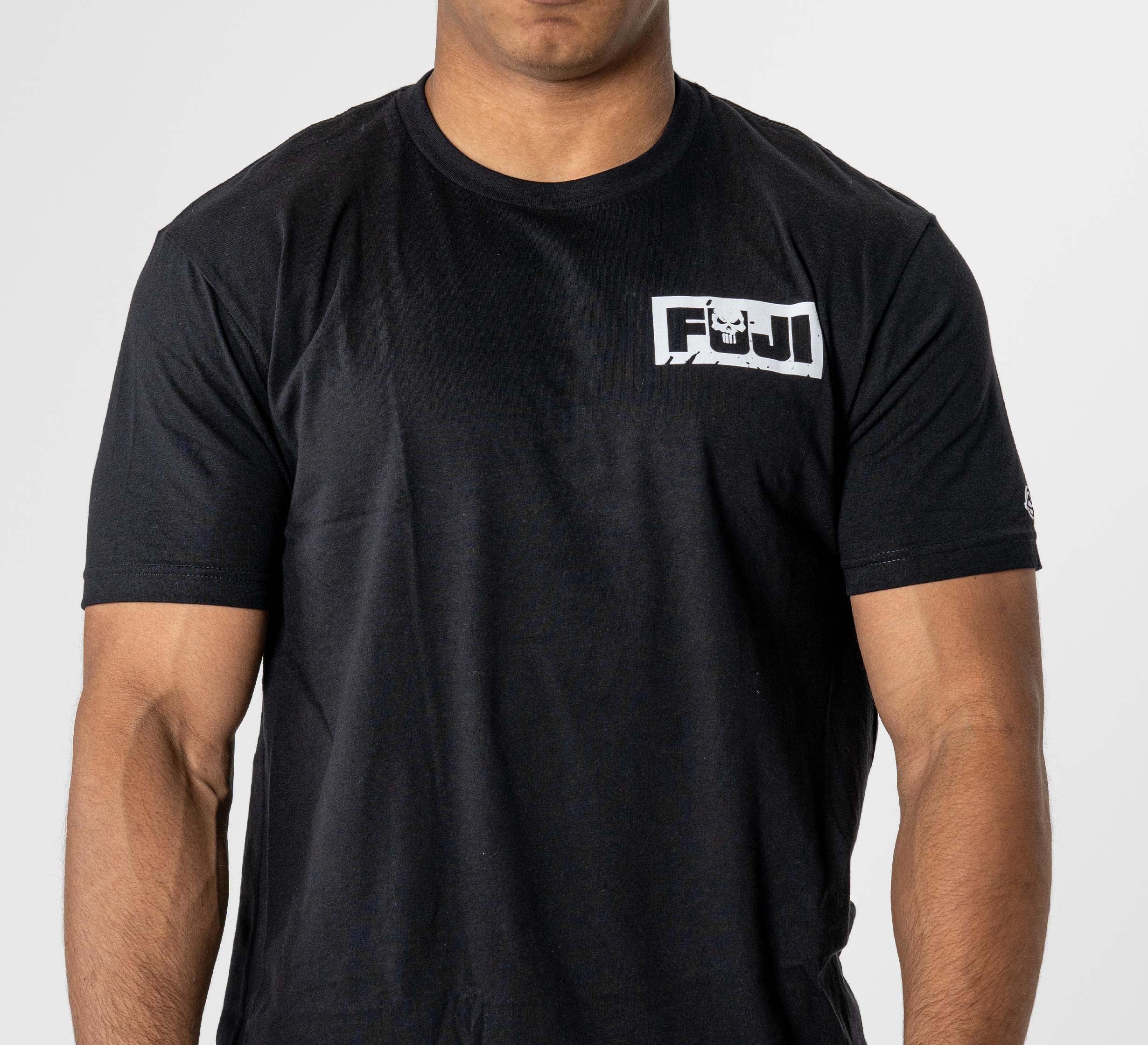 A person wearing the Punishment T-Shirt Black, featuring a white and black FUJI logo on the upper left chest, stands against a plain white background.