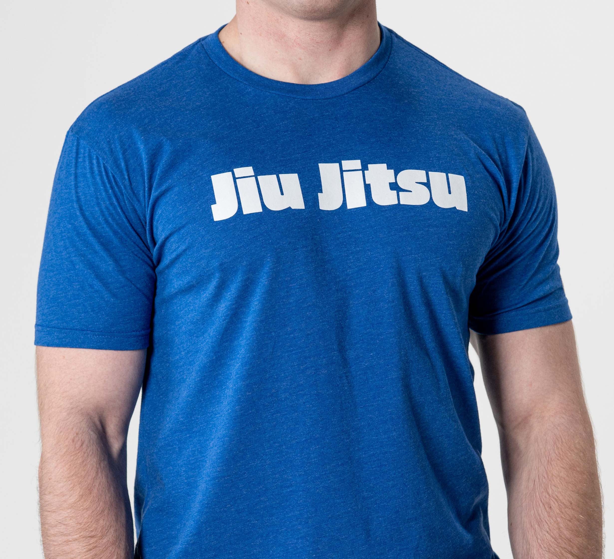 A person wearing the Jiu Jitsu Player T-Shirt Blue, which features bold white "Jiu Jitsu" lettering across the chest. The background is plain and the person's head is partially out of frame.