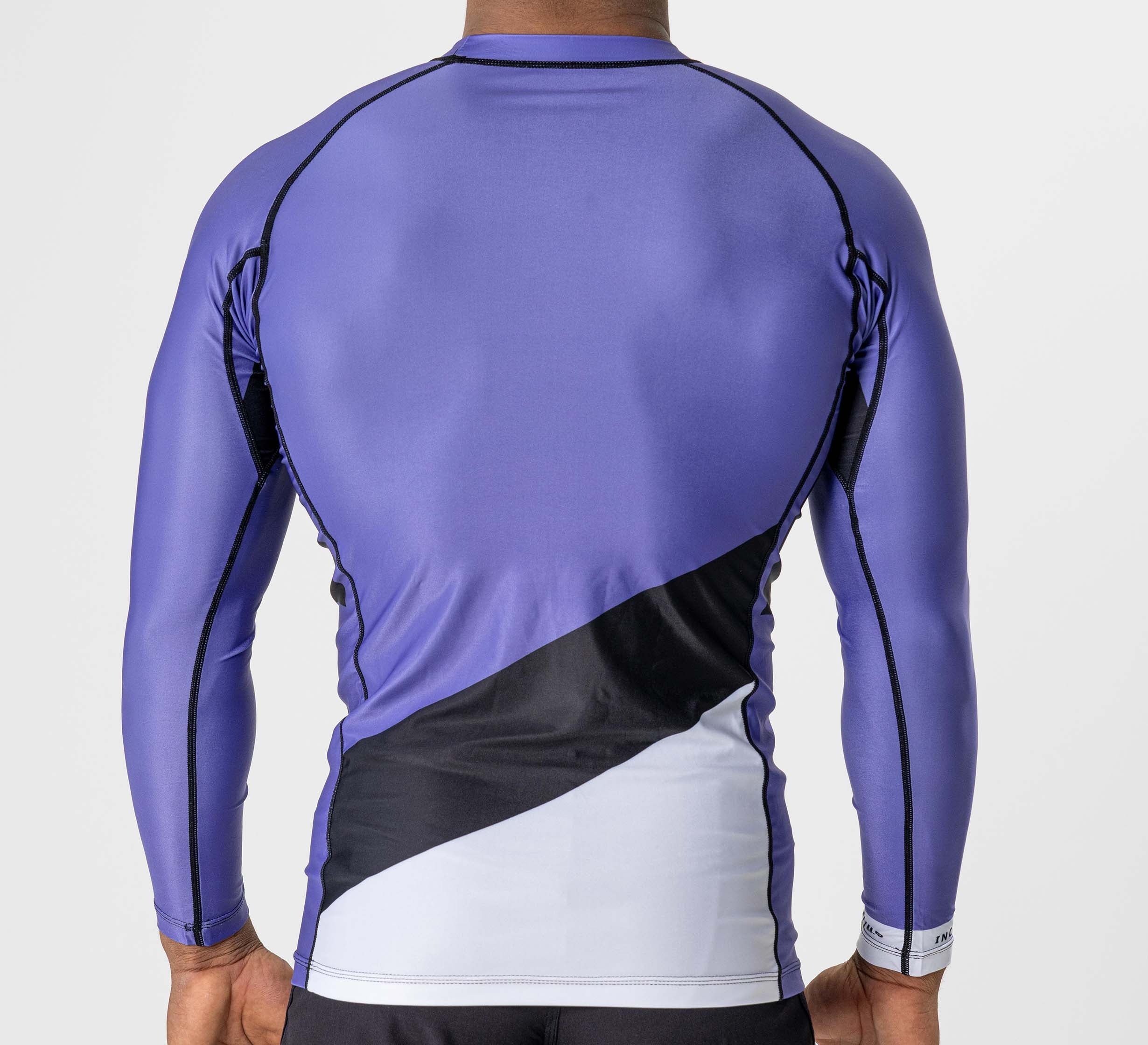 A person wears the Pacer Flex Lite Long Sleeve Rashguard in purple, featuring black and white geometric panels, shown from the back against a plain light background.