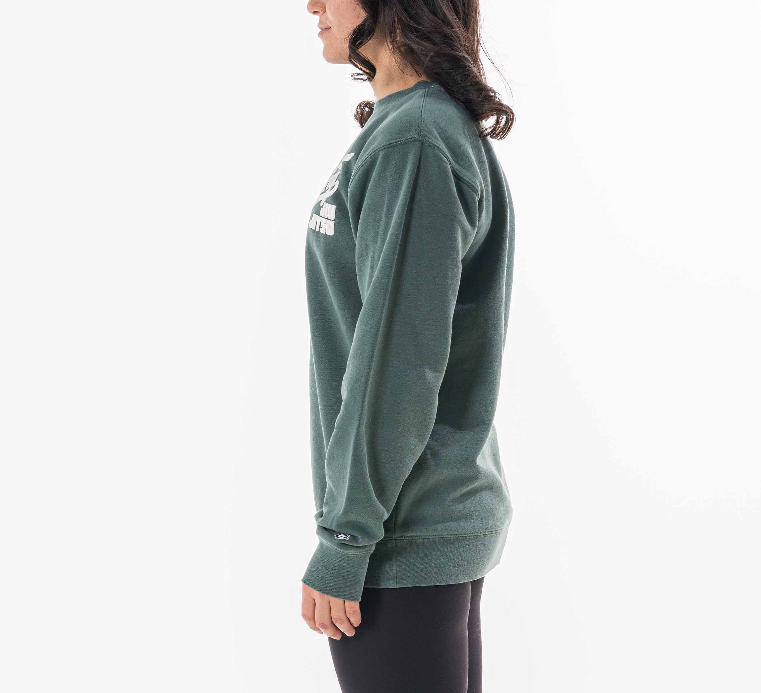 A woman with long dark hair models the Womens Signature Crewneck Green, standing in profile facing left against a plain white background.