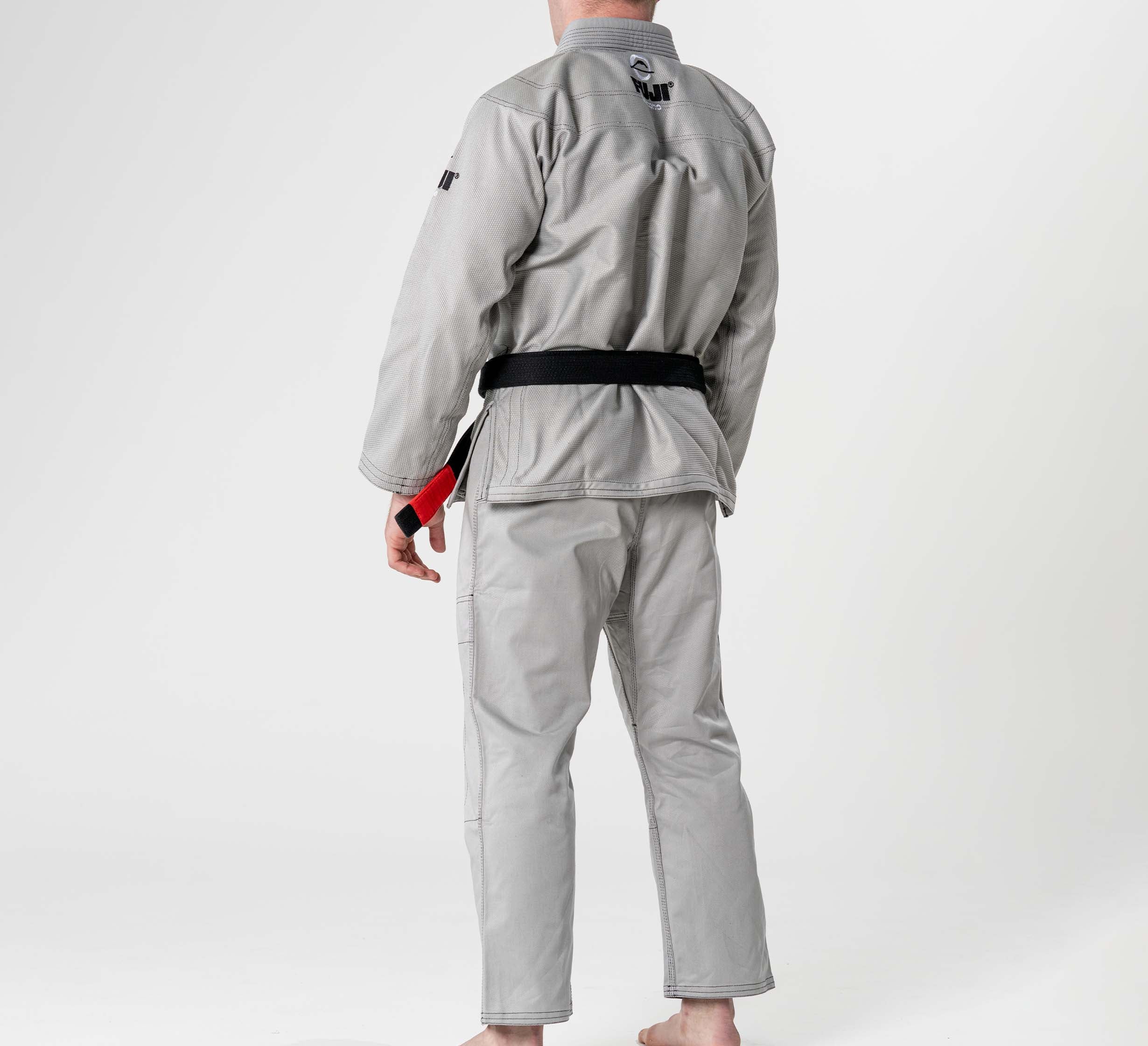 A person wearing the Lightweight BJJ Gi Grey and a black belt stands barefoot on a white background, facing away from the camera.