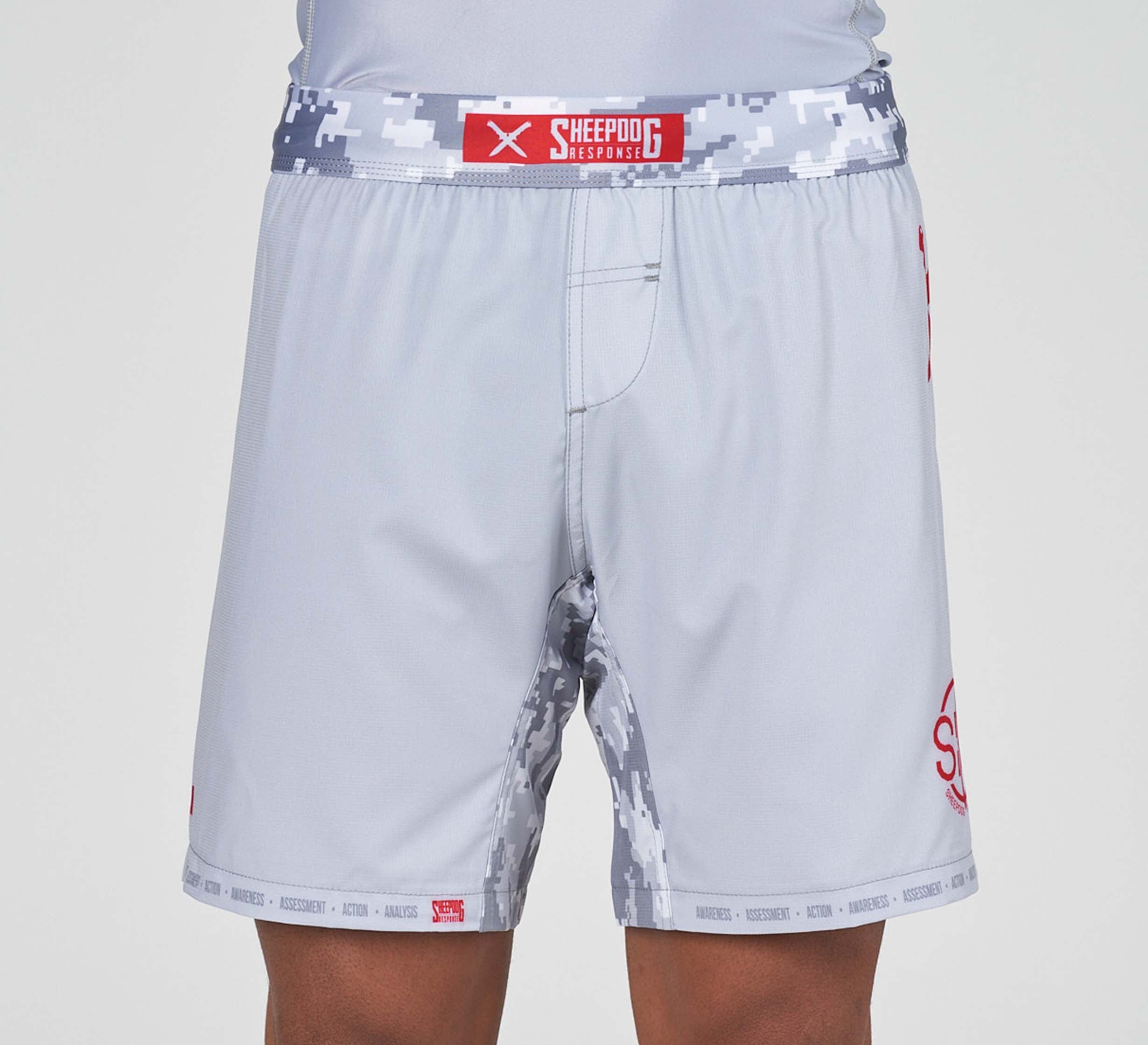 Person wearing Sheepdog Response Flex Lite Shorts Grey with a digital camouflage-patterned waistband and inner thigh, featuring a red Sheepdog Response logo on the waistband.