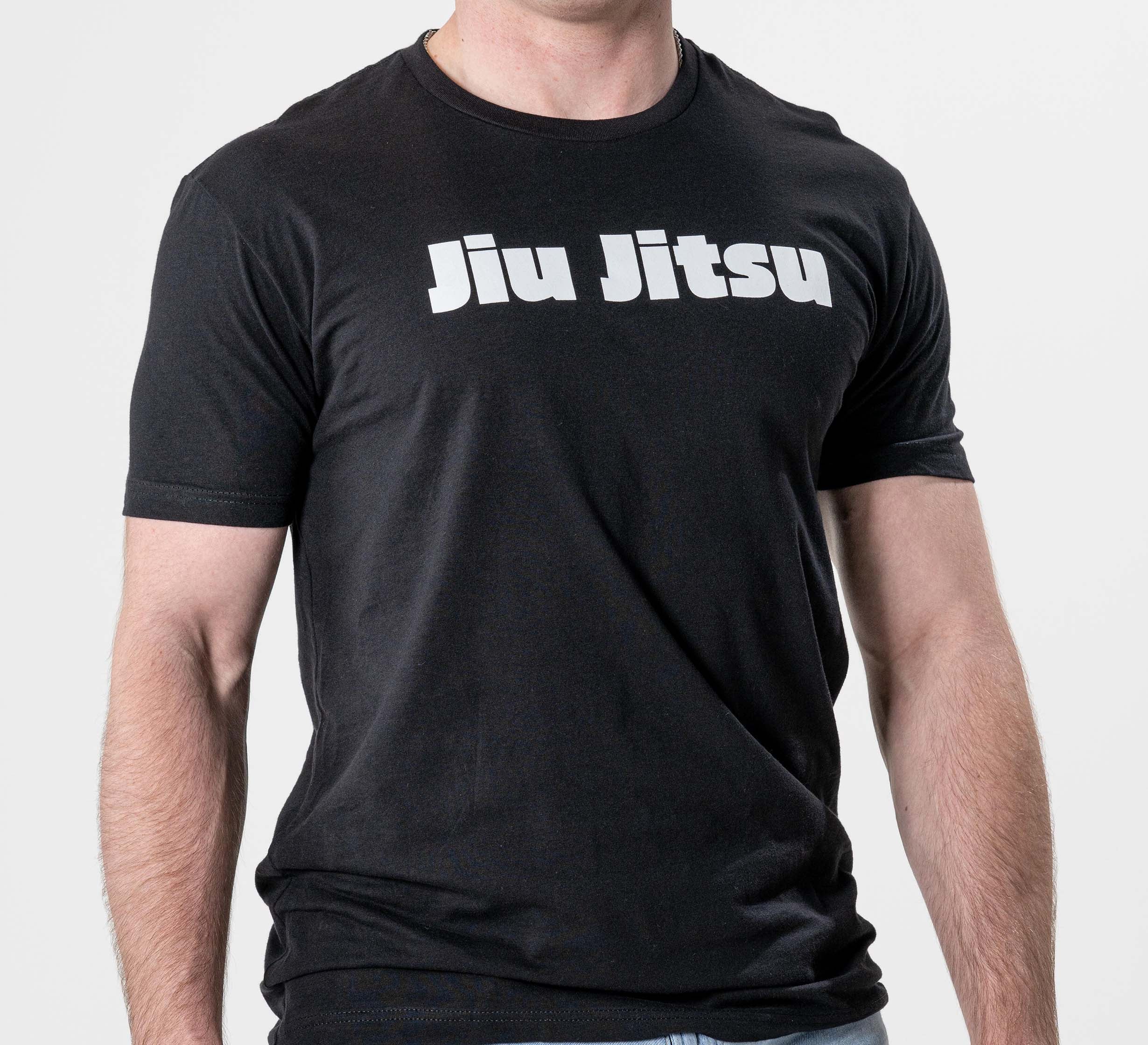 A person wears the Jiu Jitsu Player T-Shirt Black, featuring "Jiu Jitsu" in bold white letters across the chest, while standing against a plain white background.