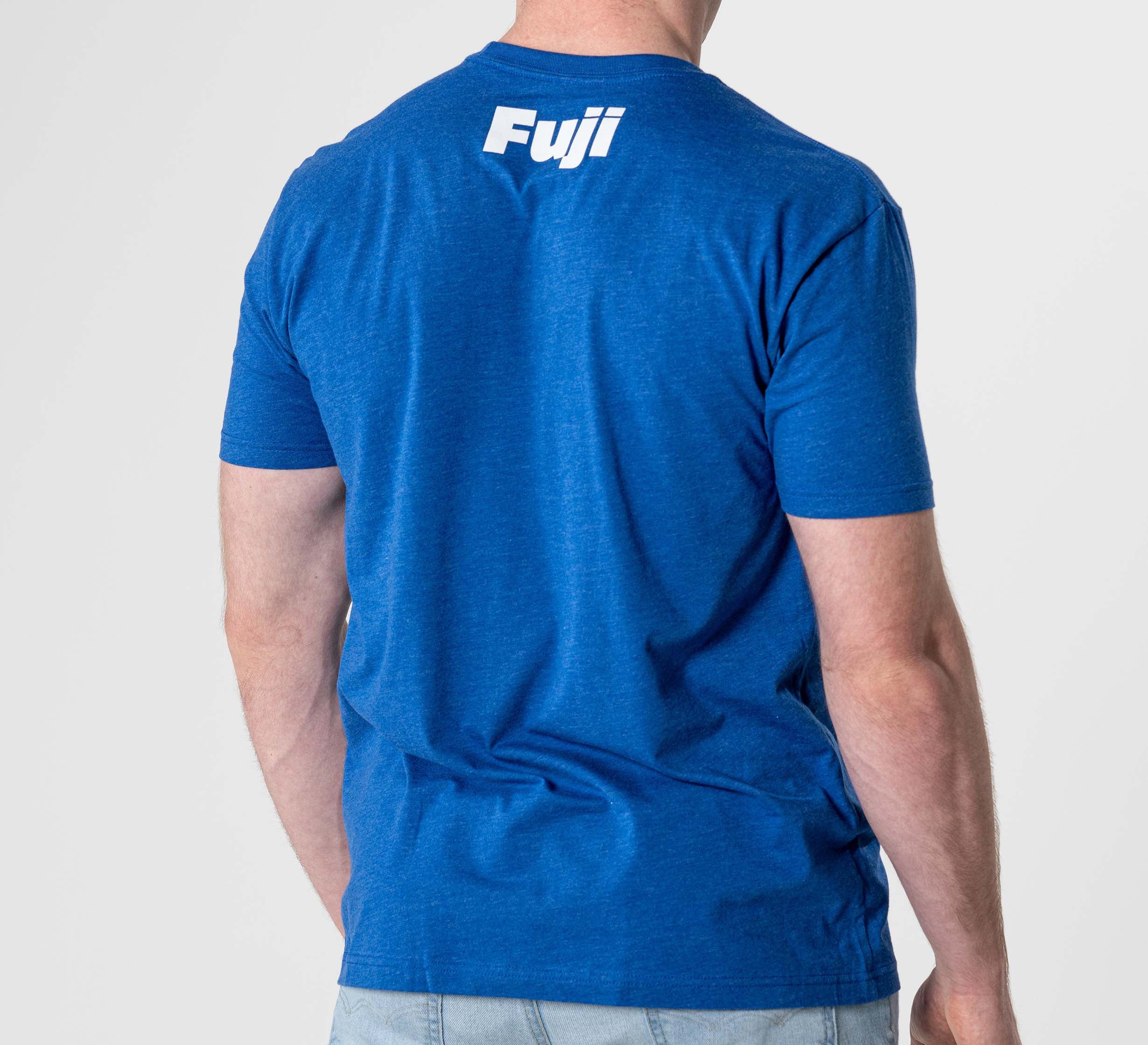 A person wearing the Jiu Jitsu Player T-Shirt Blue, featuring "Fuji" printed in white on the upper back, is facing away from the camera.
