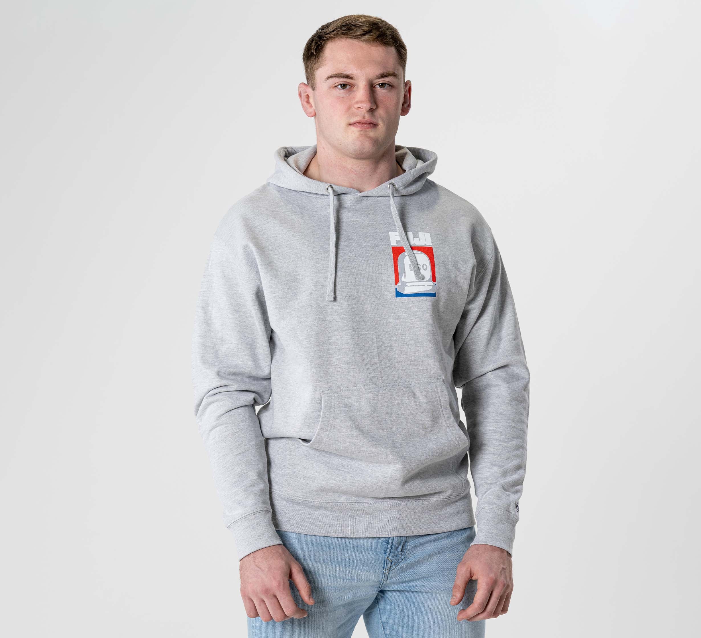 A young man faces forward in the Submit Your Ego Hoodie Heather Grey, featuring a colorful graphic, paired with light blue jeans against a plain white background.