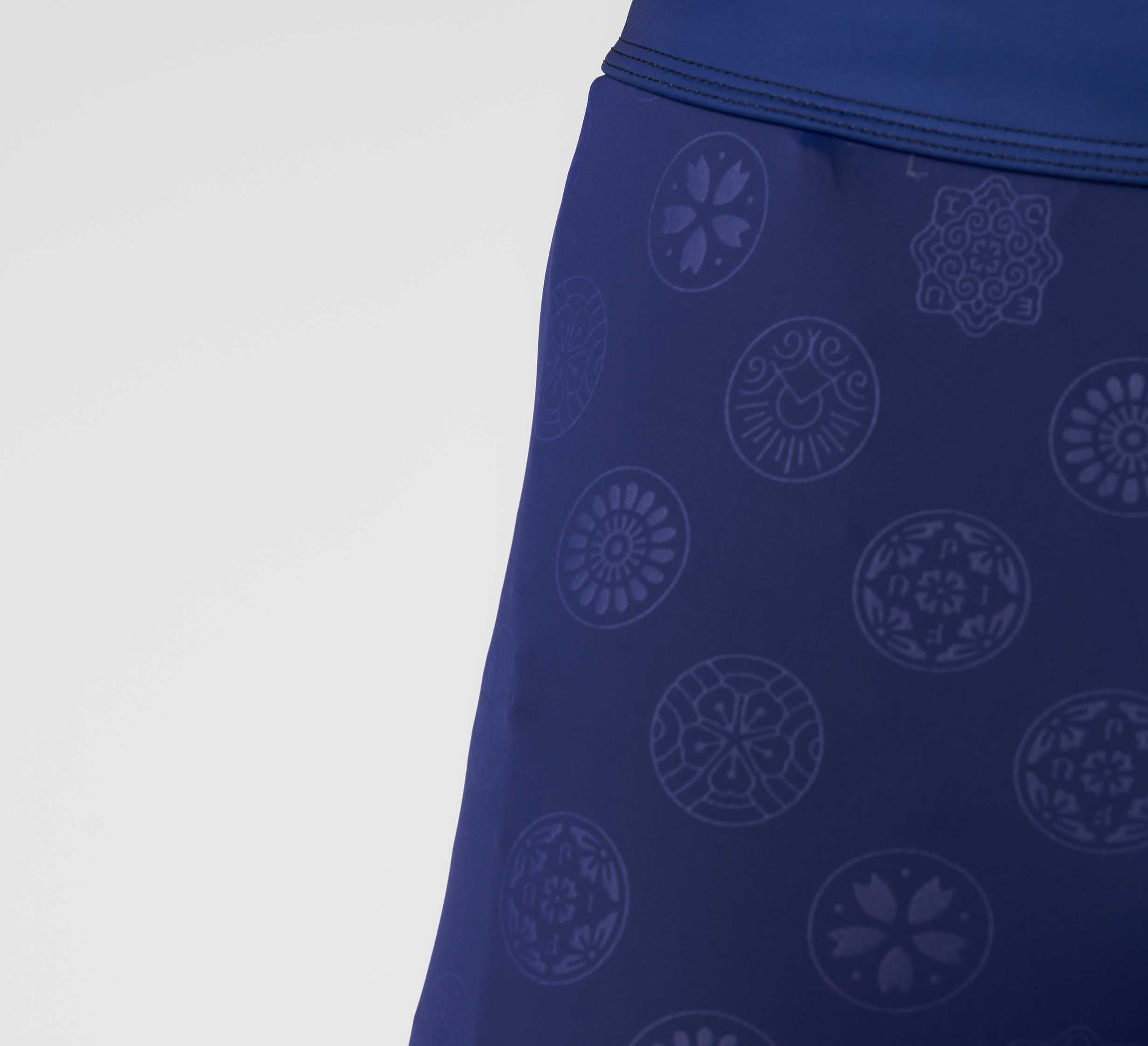 Close-up of the Shogun Heat Gear Spats Navy, featuring blue fabric with subtle circular patterns and floral motifs, shown against a plain light background.