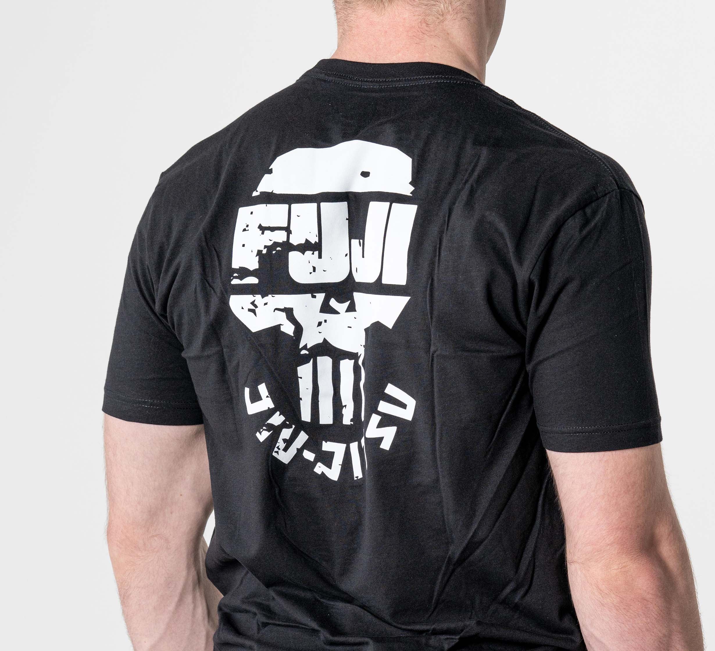 A person wears the Punishment T-Shirt Black, featuring a bold white stylized skull graphic and "FUJI" in distressed letters on the back. The background is plain and light-colored.