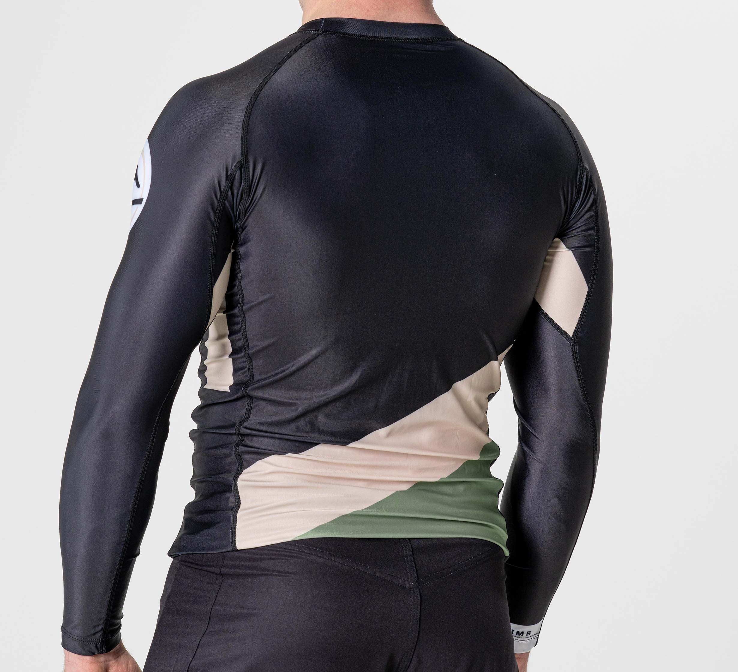 A person wearing the Pacer Flex Lite Long Sleeve Rashguard Black, featuring beige and green geometric patterns on the sides and lower back, shown from behind against a plain white background.