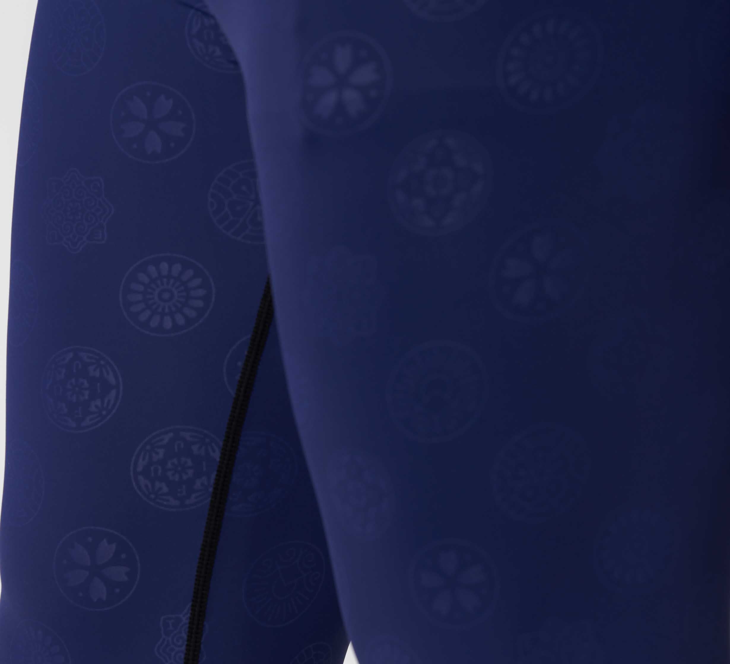 Close-up of Shogun Heat Gear Spats Navy athletic leggings, showcasing a subtle circular floral pattern in deep blue with a lighter shade and a visible black vertical seam.