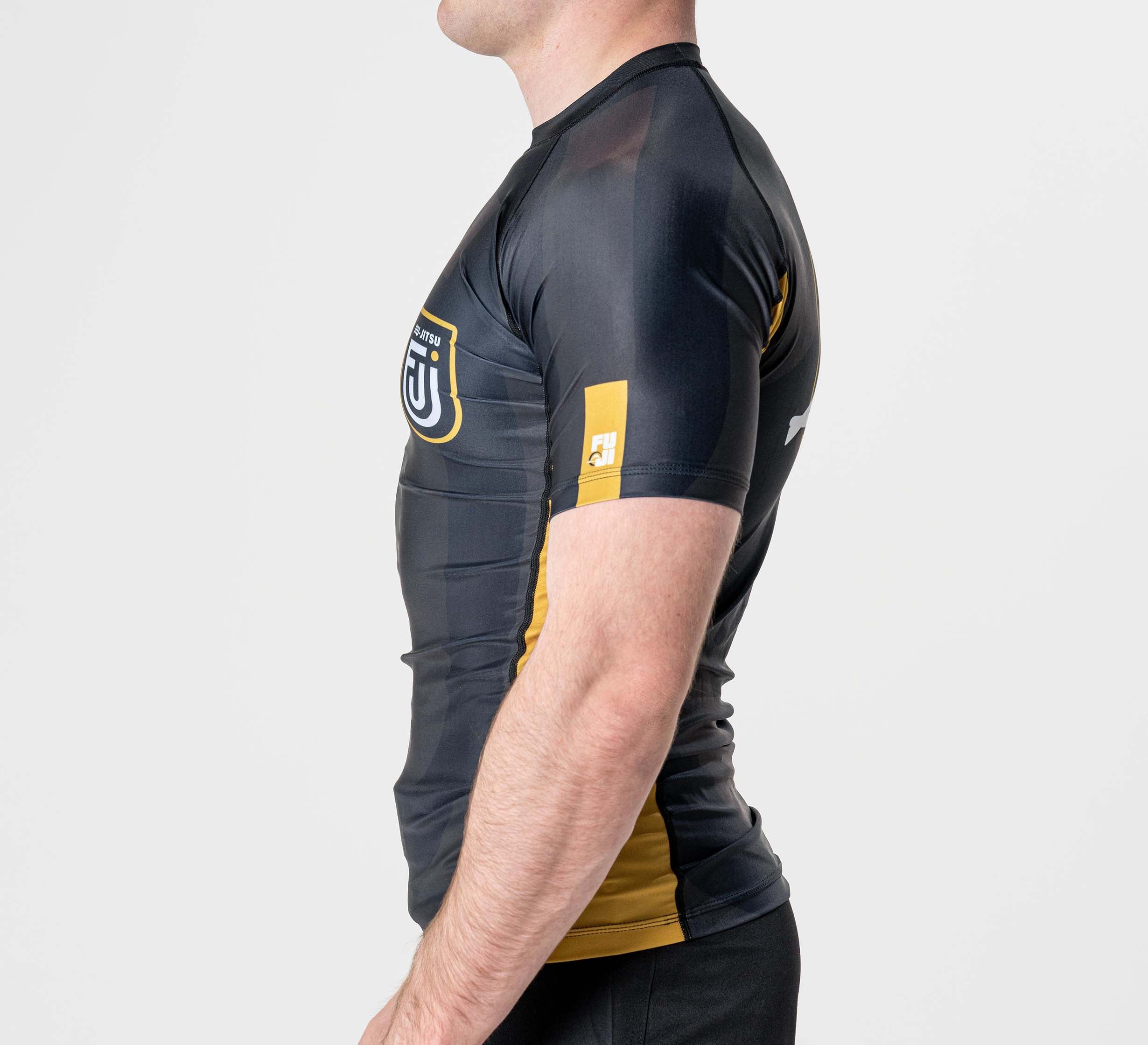 A person wearing the Rebel Flex Lite Rashguard Black stands in profile against a plain white background, showing only their upper body.