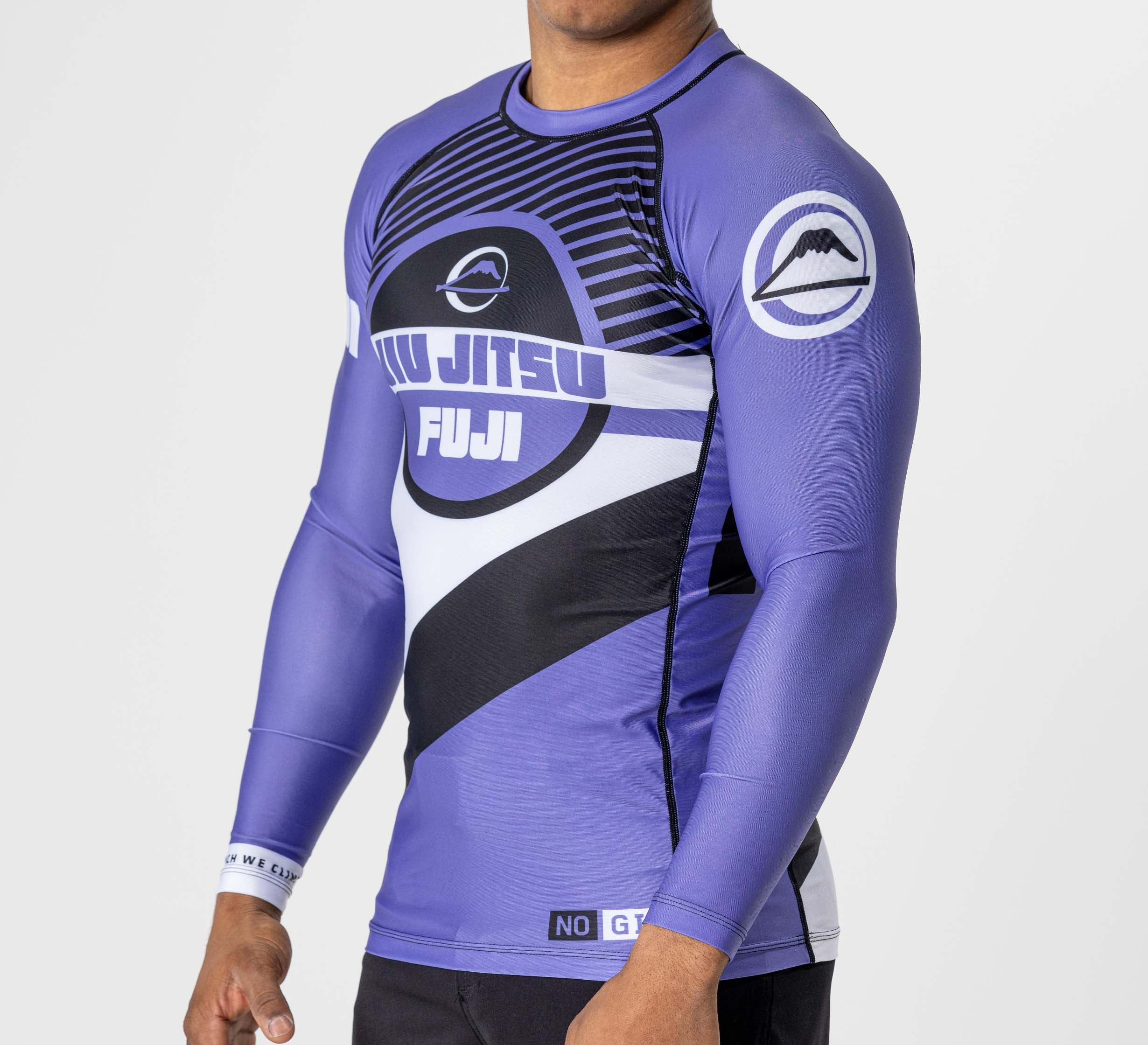 A person wears the Pacer Flex Lite Long Sleeve Rashguard in purple with black and white graphics and logos, standing against a plain light background.