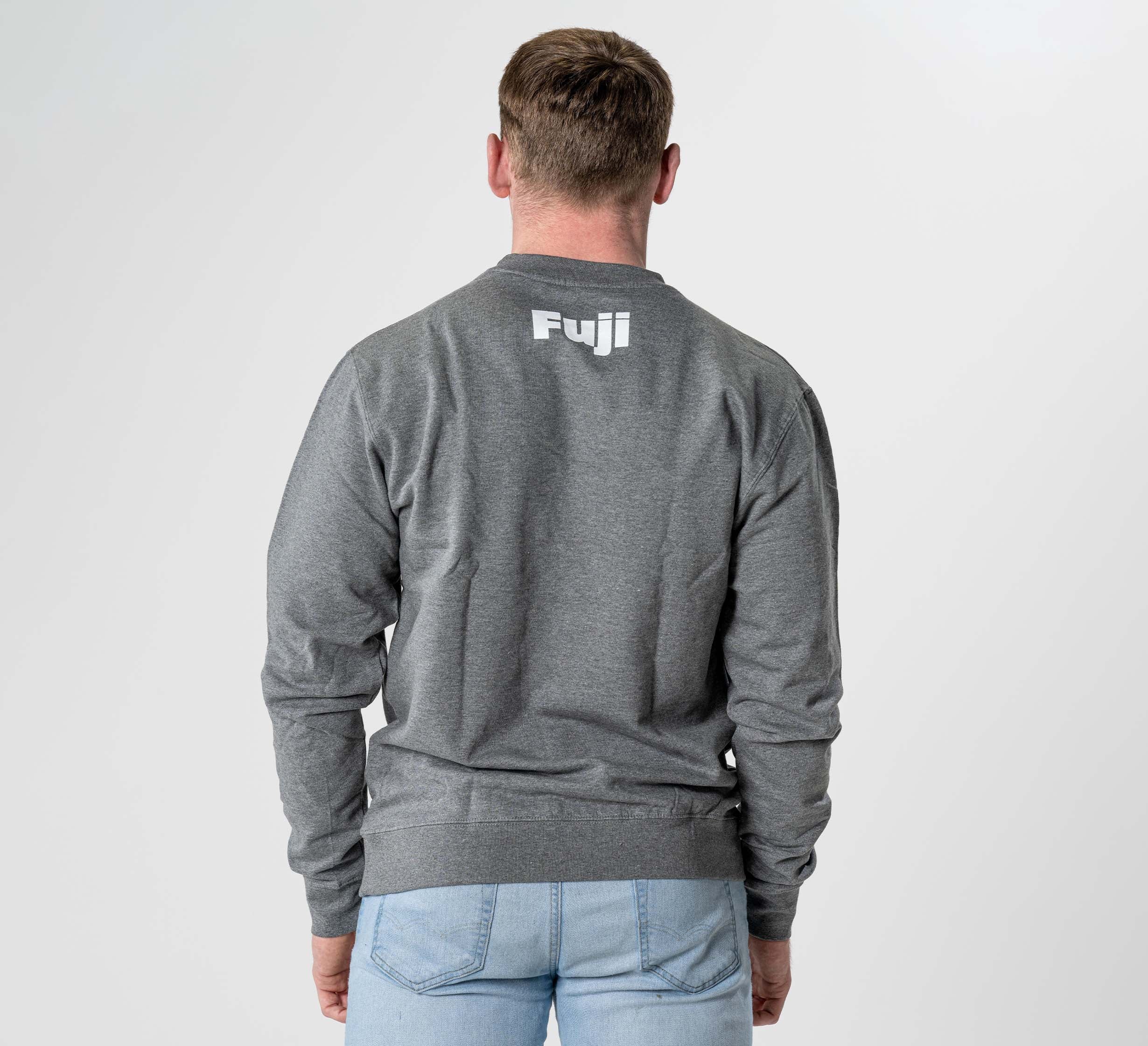 A person wearing the Jiu Jitsu Player Crewneck in heather grey, featuring "Fuji" printed in white on the back, stands facing away from the camera against a plain light background.