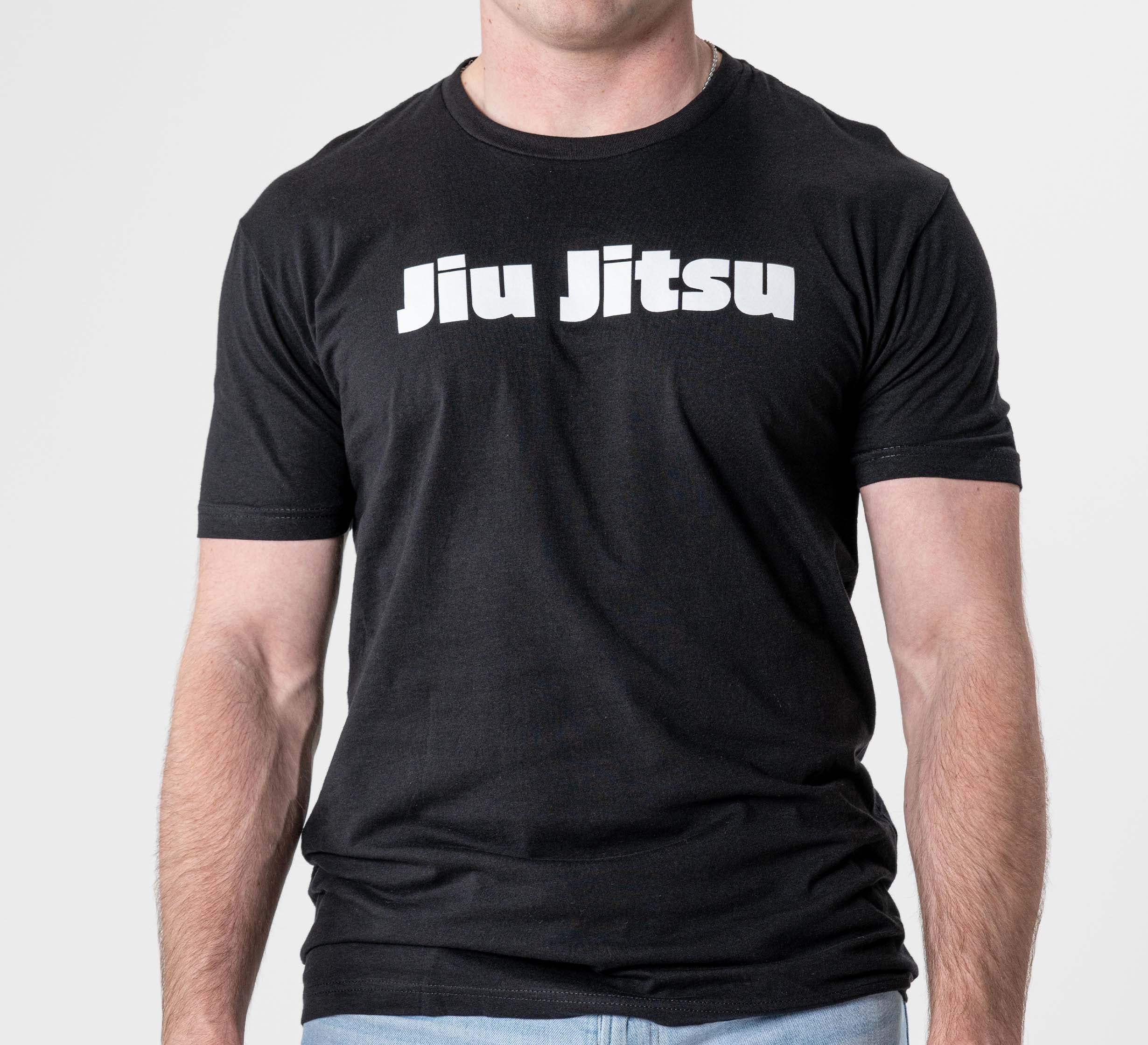 A person wears the Jiu Jitsu Player T-Shirt Black, featuring bold white "Jiu Jitsu" lettering on the chest, standing against a plain light background.