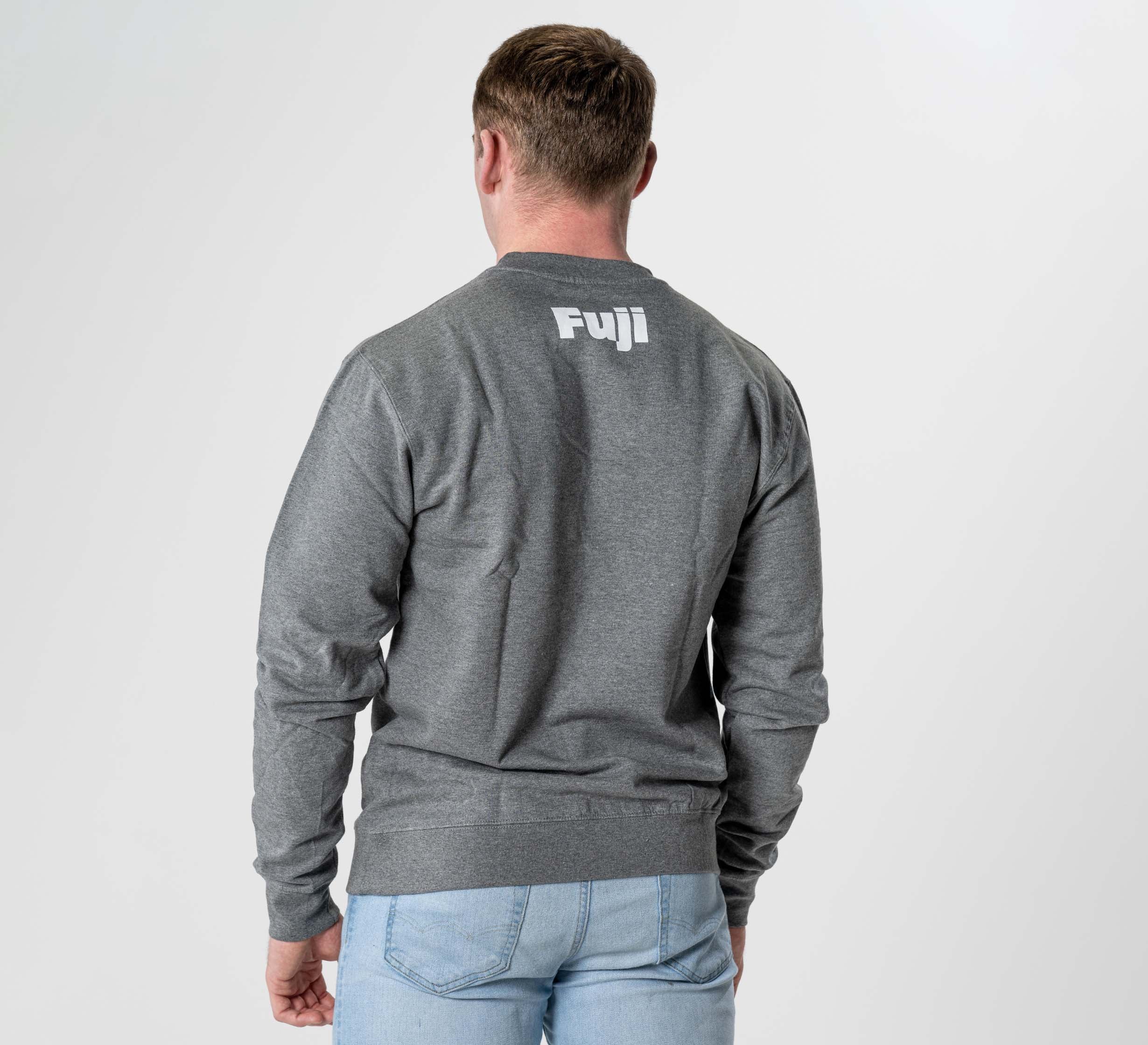 A person wearing the Jiu Jitsu Player Crewneck in heather grey, featuring "Fuji" in white on the upper back, stands against a plain light background with their back to the camera.