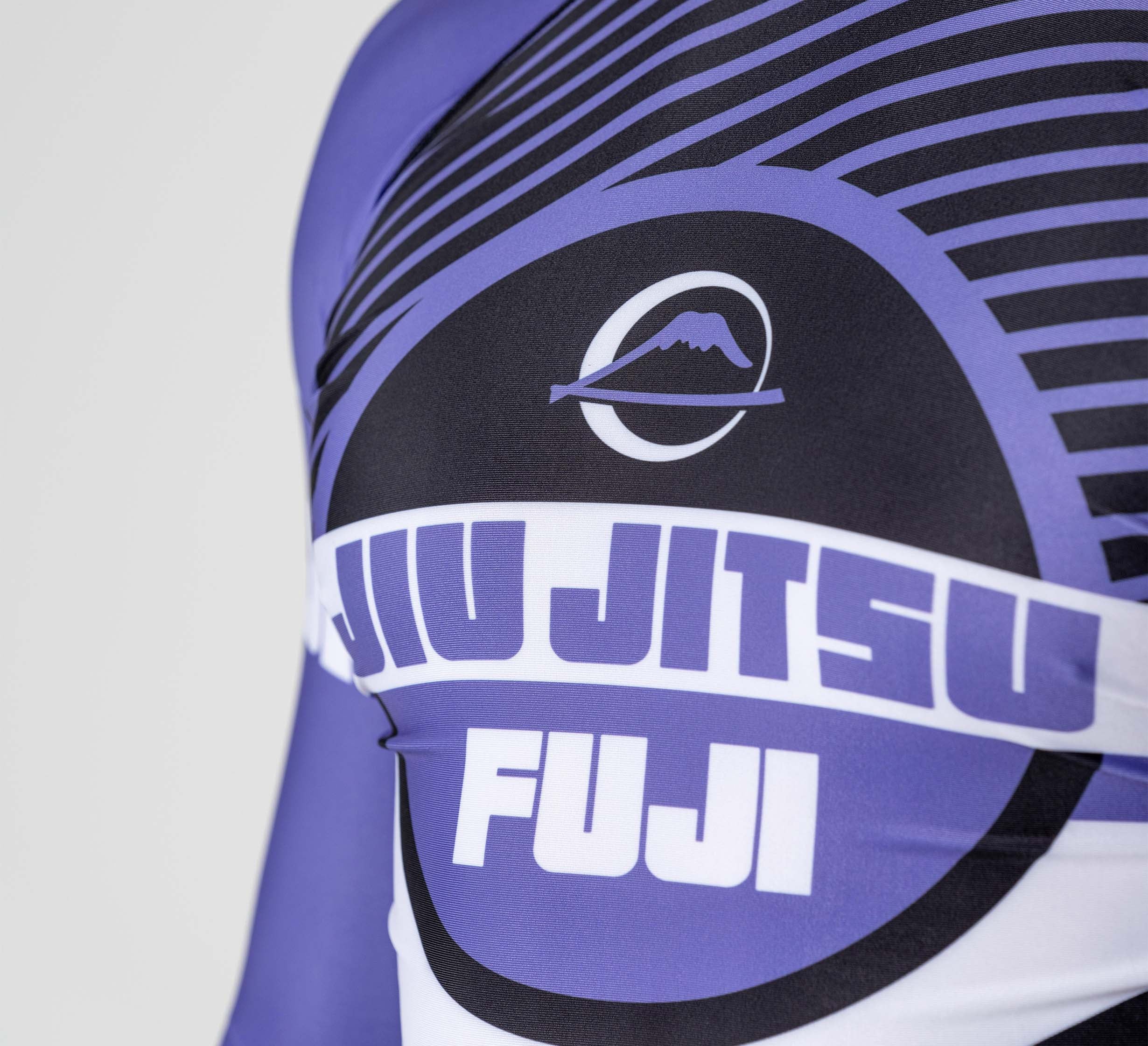 Close-up of the Pacer Flex Lite Long Sleeve Rashguard Purple, a sports shirt with “JIU JITSU” and “FUJI” text, a mountain-in-circle logo, and a dynamic purple and black striped design.