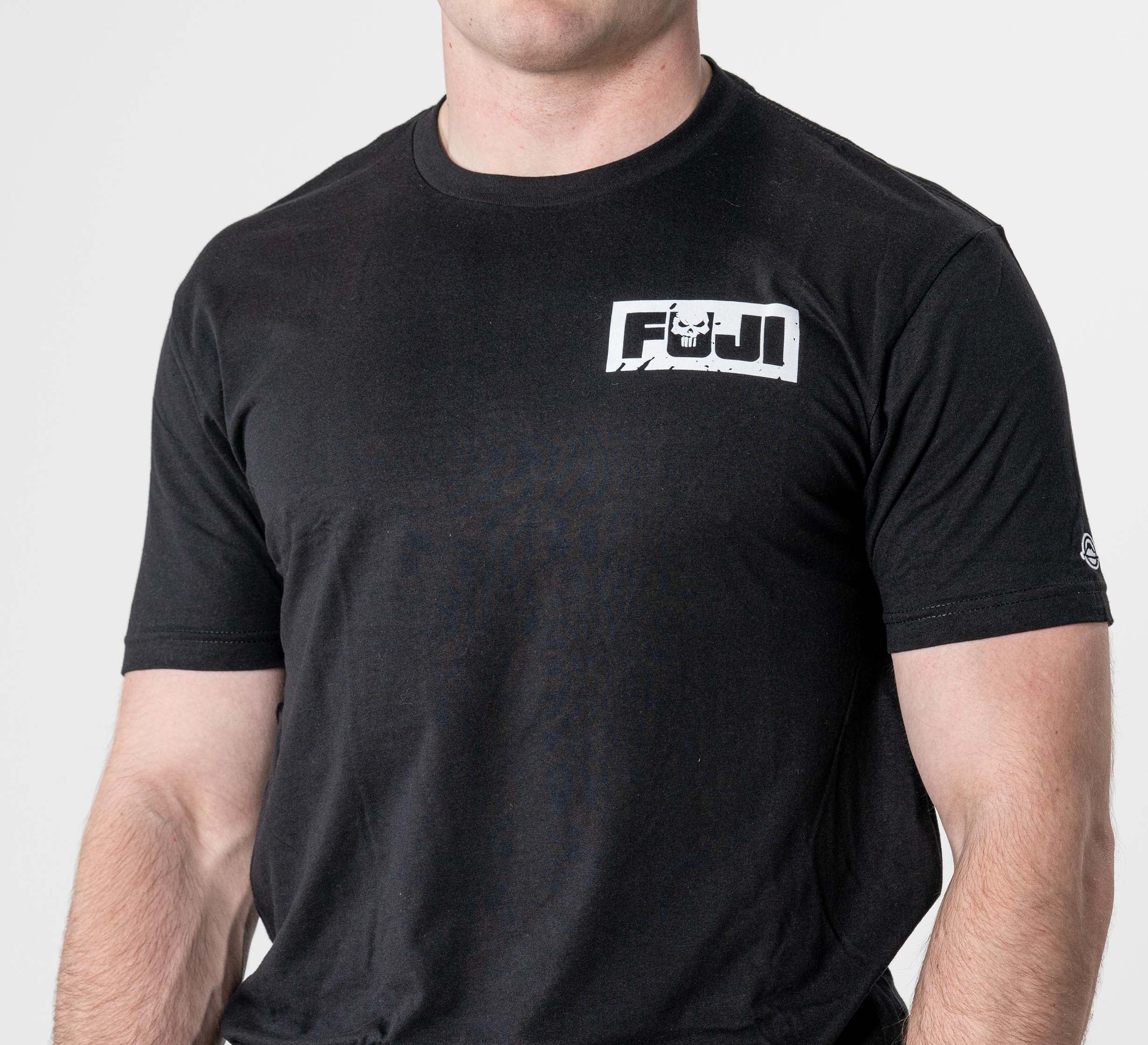 A person wearing the Punishment T-Shirt Black, featuring a white FUJI logo and stylized mountain design on the upper left chest, stands against a plain white background.