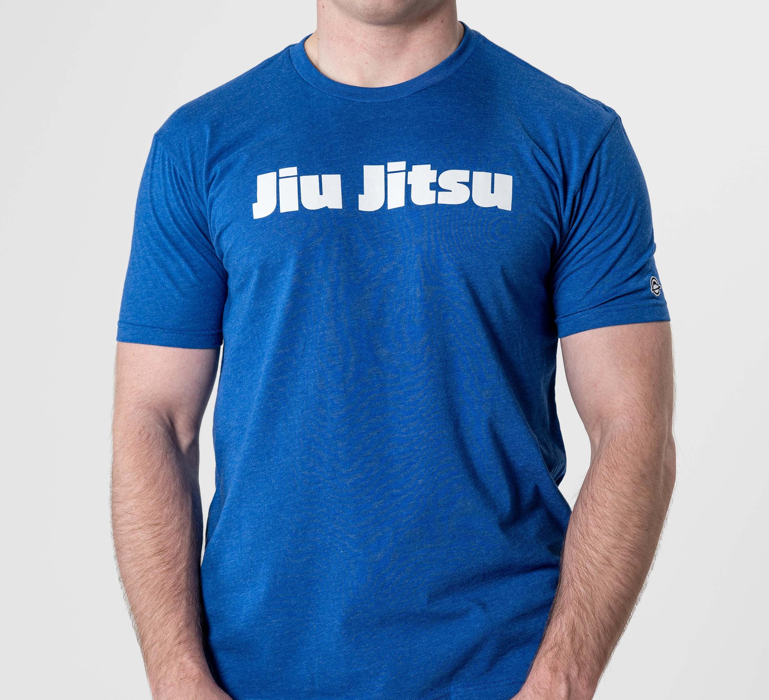 A person wearing the Jiu Jitsu Player T-Shirt Blue, featuring "Jiu Jitsu" in bold white letters across the chest, stands against a plain light background.