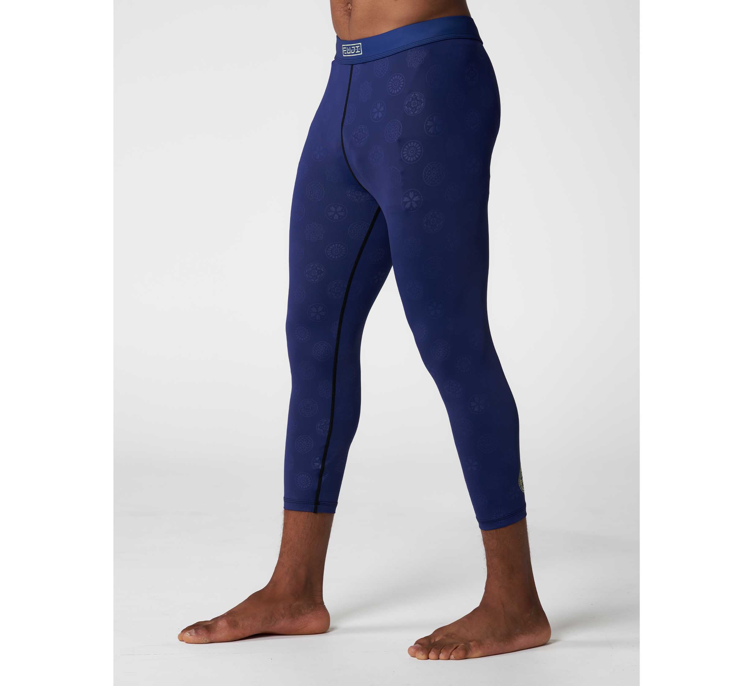 A person models the Shogun Heat Gear Spats Navy—form-fitting, patterned athletic leggings—in navy blue, barefoot on a white background with only their lower torso and legs visible.