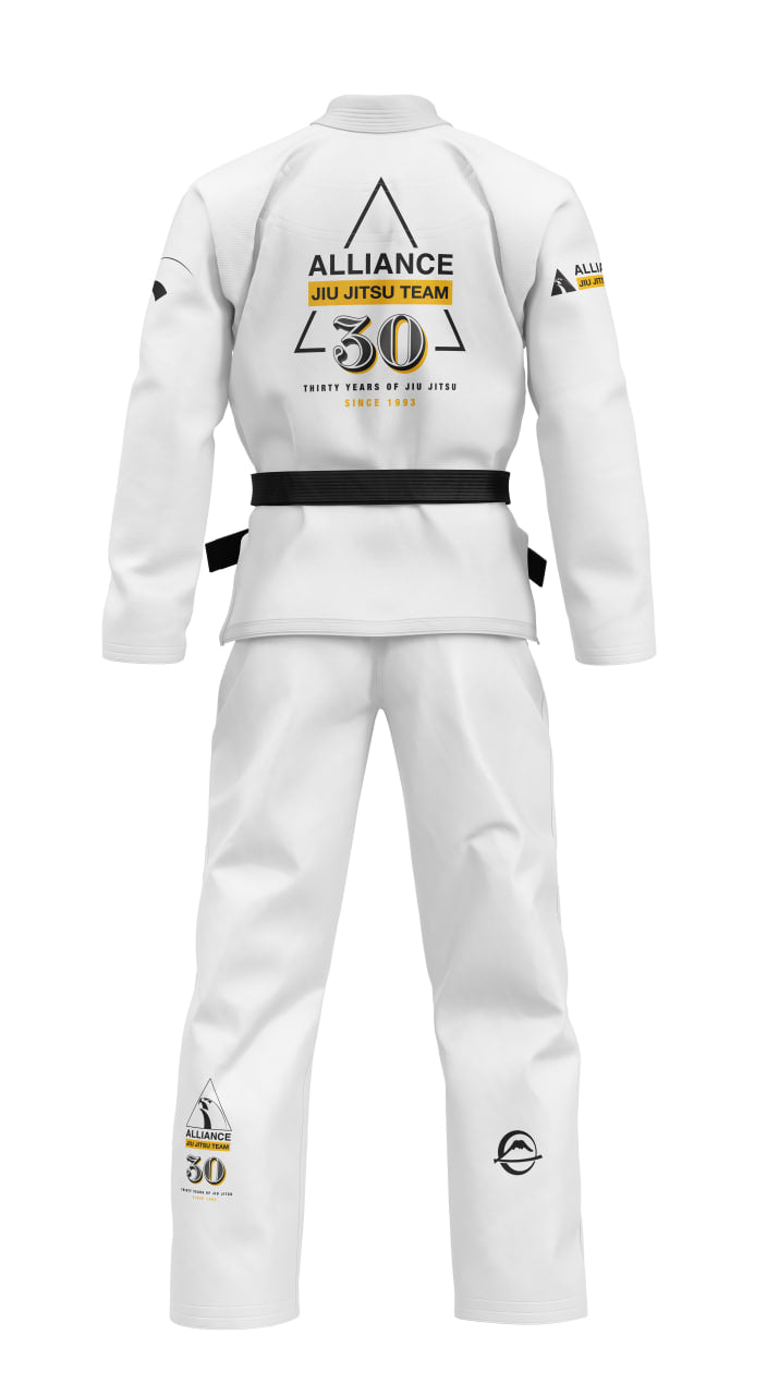 The Womens Alliance Limited Edition 30th Anniversary BJJ Gi White is shown from the back with Alliance Jiu Jitsu Team text, a black belt, gold and black 30th anniversary logo, and extra team/event logos on the sleeves and pants.