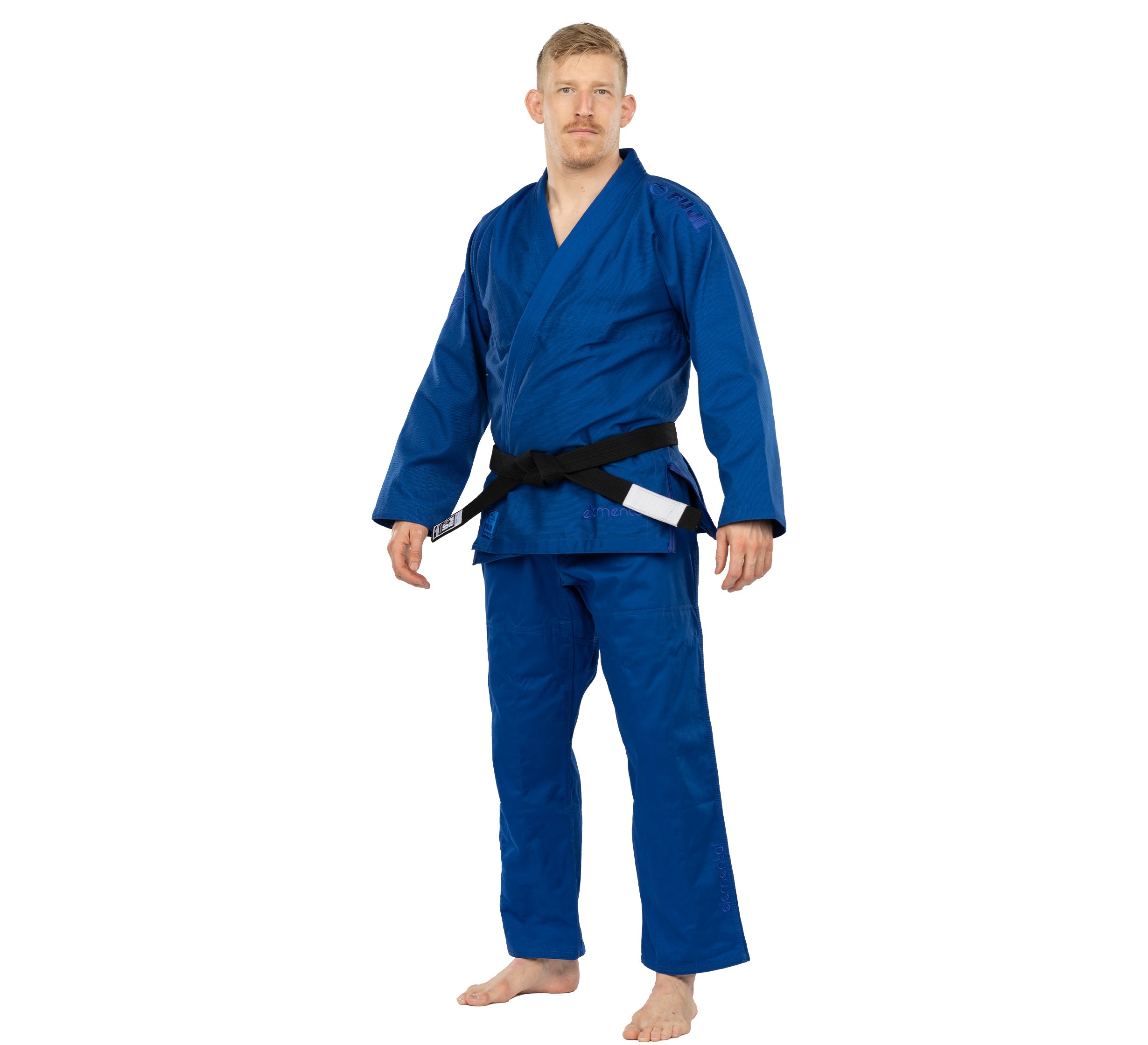 A person stands barefoot, dressed in the Elemental BJJ Gi Blue with a black belt, looking forward with a neutral expression against a plain white background.