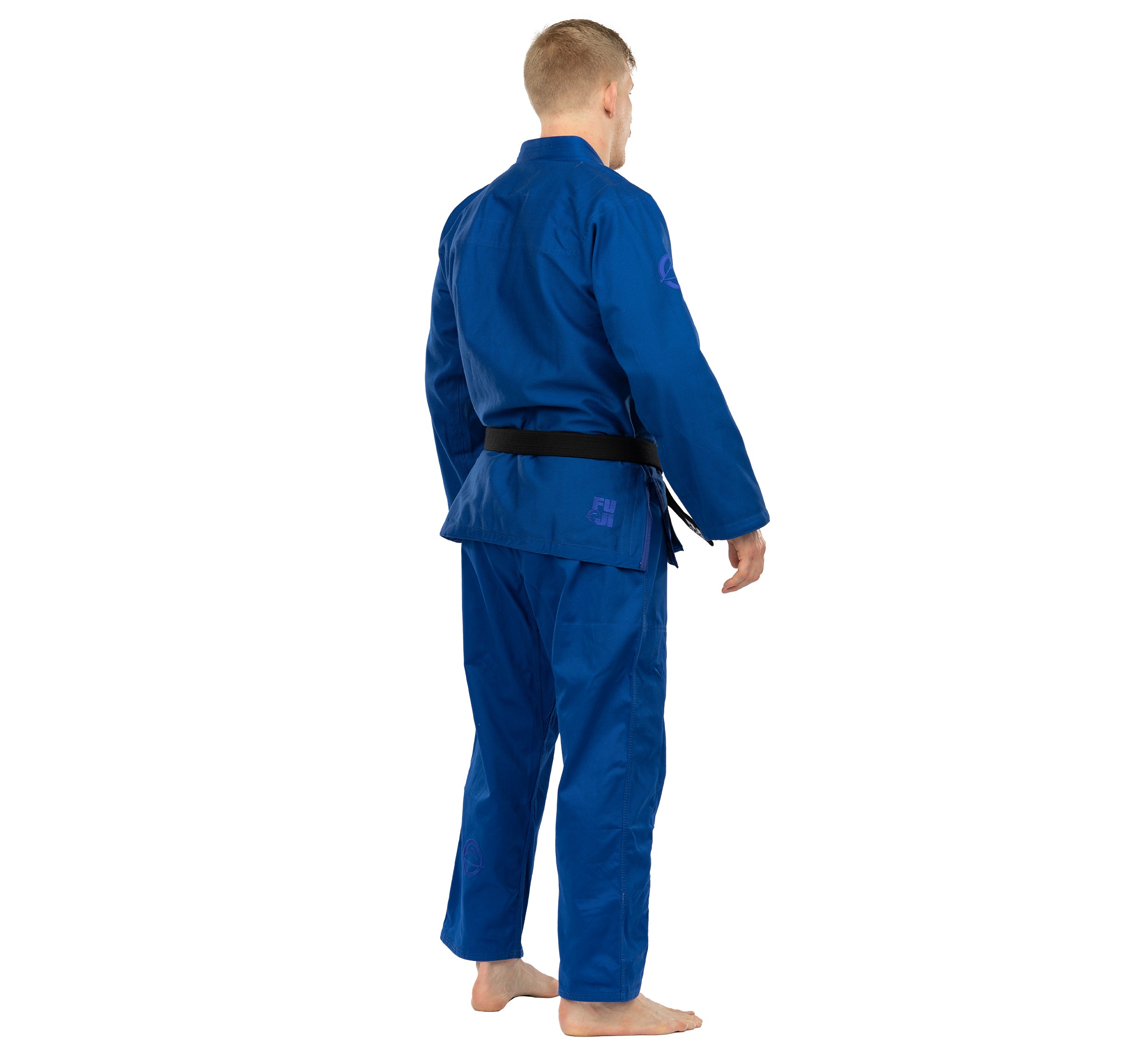 A person stands barefoot, facing away from the camera in an Elemental BJJ Gi Blue with a black belt, against a plain white background.
