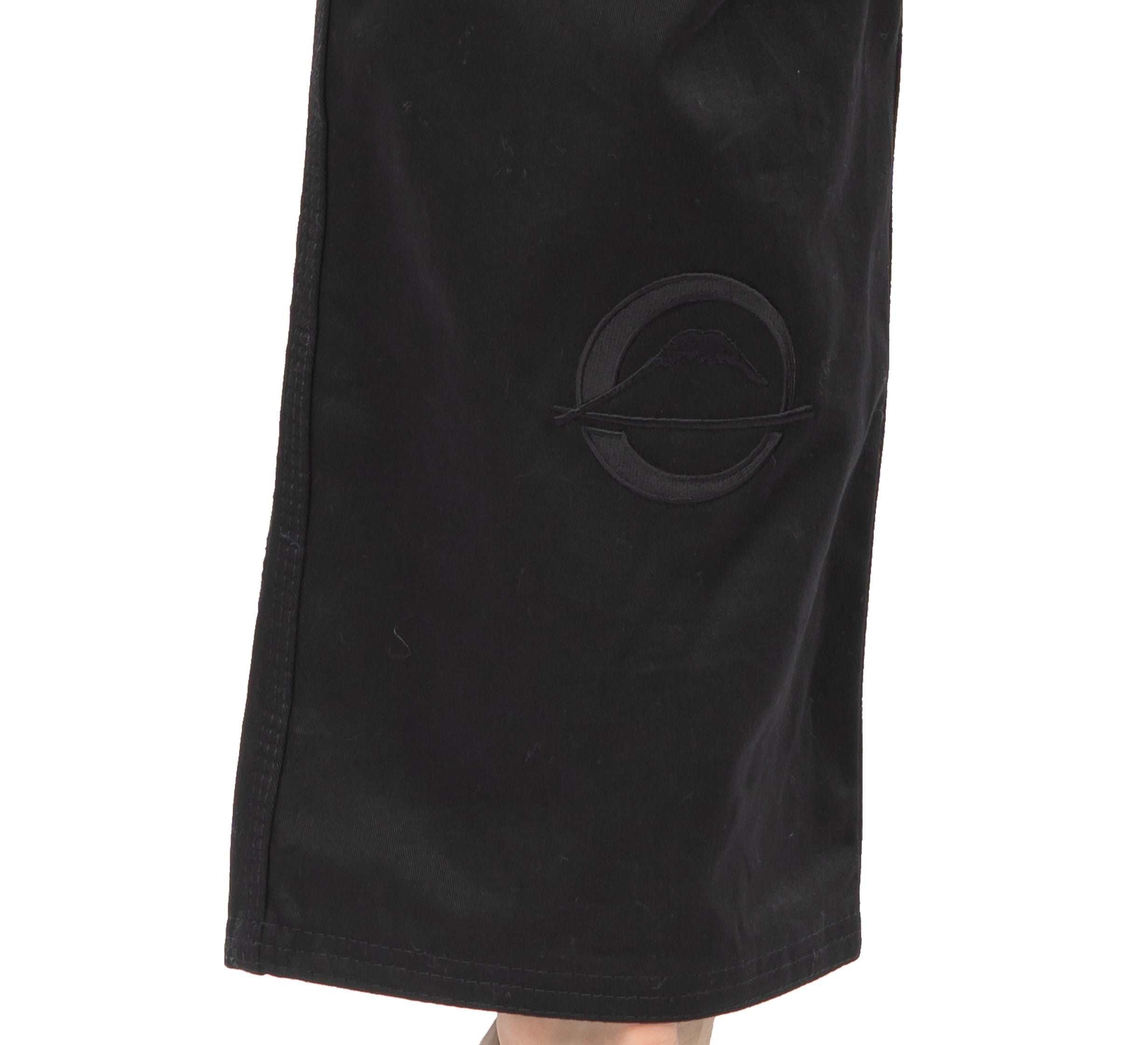 A close-up of the lower part of the Elemental BJJ Gi Black pant shows a subtle embroidered circular patch with a curved line.