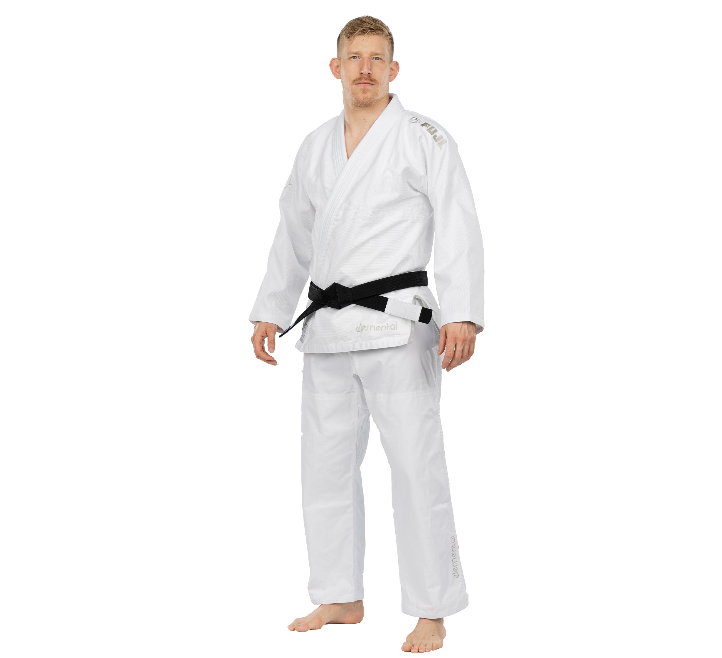 A man with short blond hair and a mustache stands barefoot, wearing the Elemental BJJ Gi White and a black belt, facing forward against a plain white background.