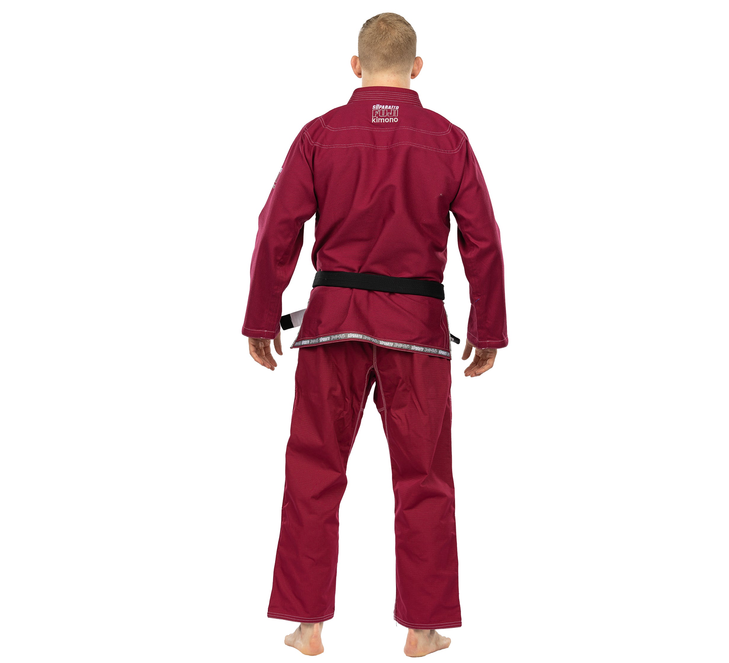 A person wearing the Suparaito BJJ Gi in Burgundy and a black belt stands barefoot, facing away from the camera against a white background.