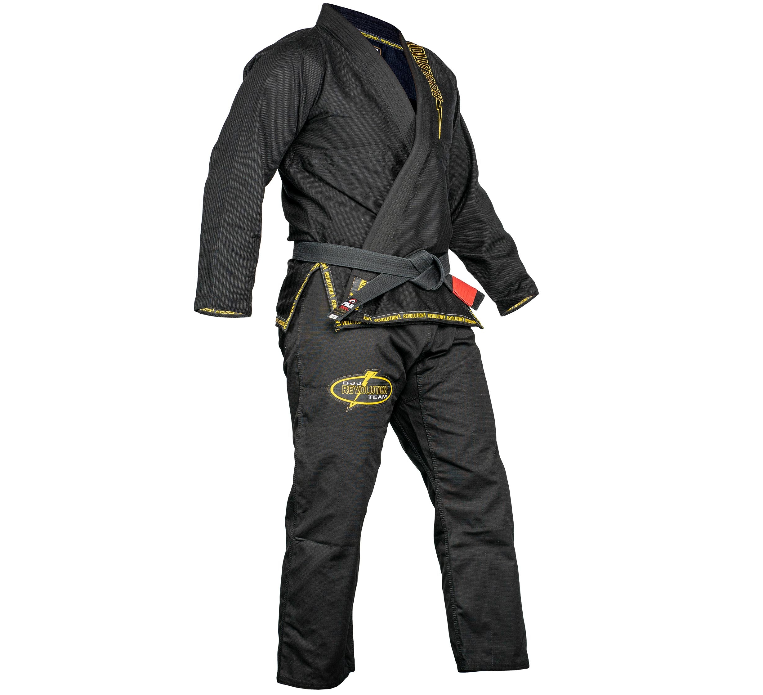 A BJJ Revolution Super Lite Kids Gi in black with yellow stitching and embroidered patches is displayed on a mannequin with a gray belt. The jacket is partially open, showing the inner lining.