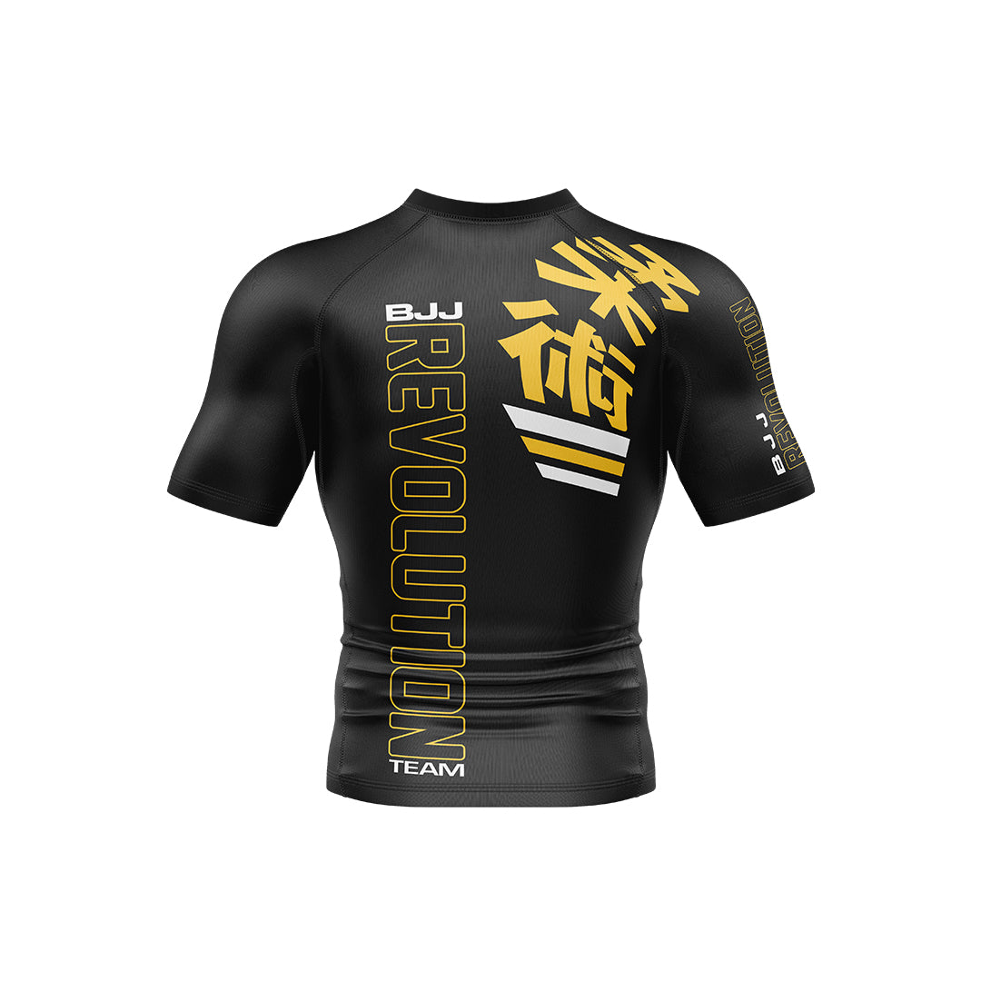 The BJJ Revolution KIDS Ranked Rashguard Short Sleeve is a black top featuring bold yellow "REVOLUTION" text and Japanese kanji on the front, with "BJJ" and "TEAM" in white plus yellow graphics on the left sleeve.