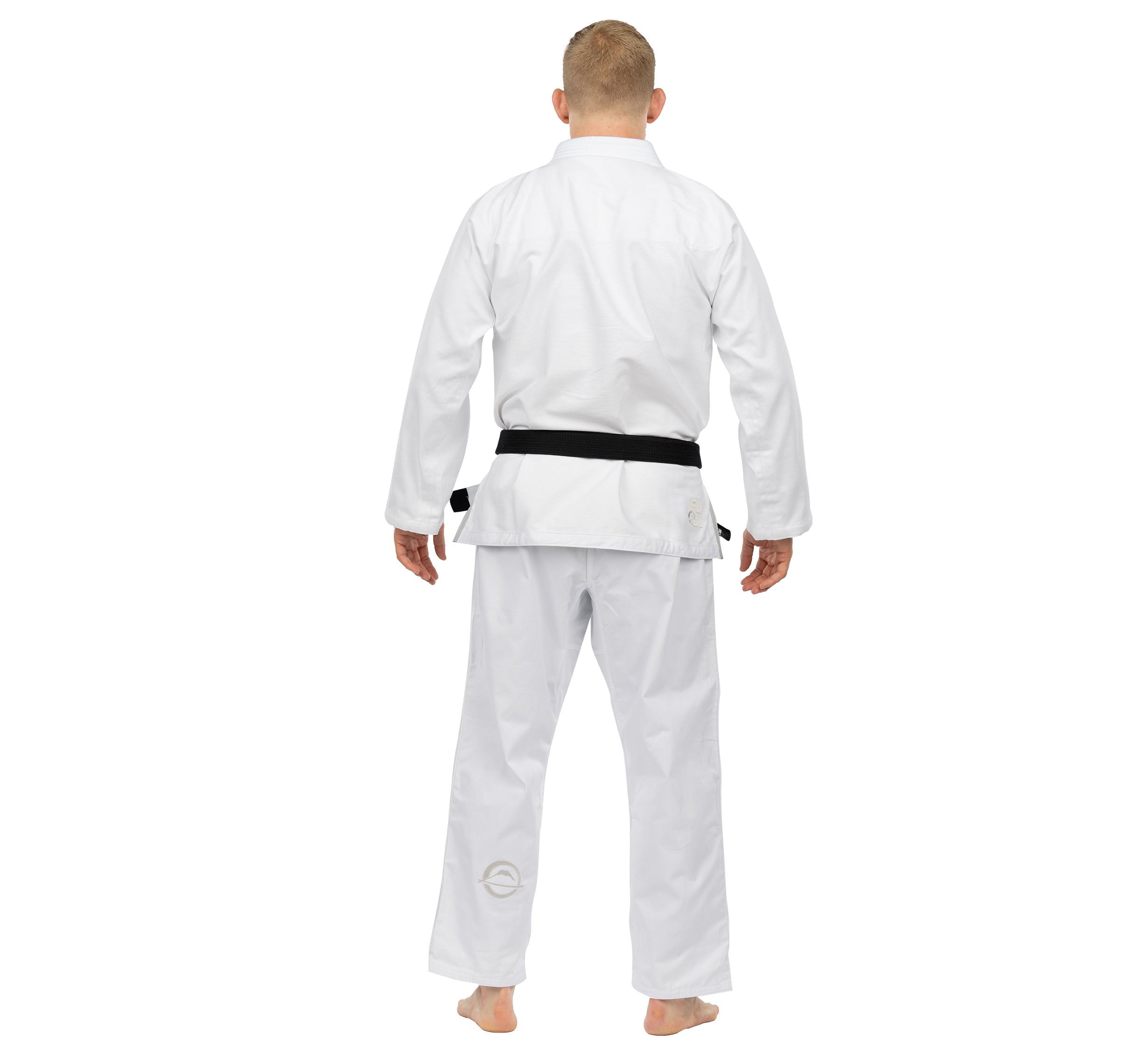A person wearing the Elemental BJJ Gi White and a black belt stands barefoot, facing away from the camera against a plain white background.