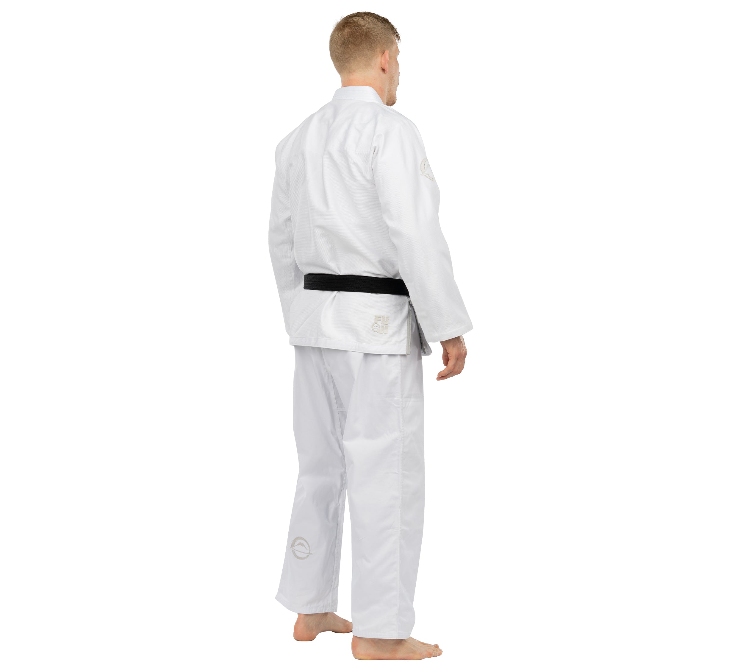 A person stands barefoot, facing away from the camera against a plain white background, wearing the Elemental BJJ Gi White with a black belt.