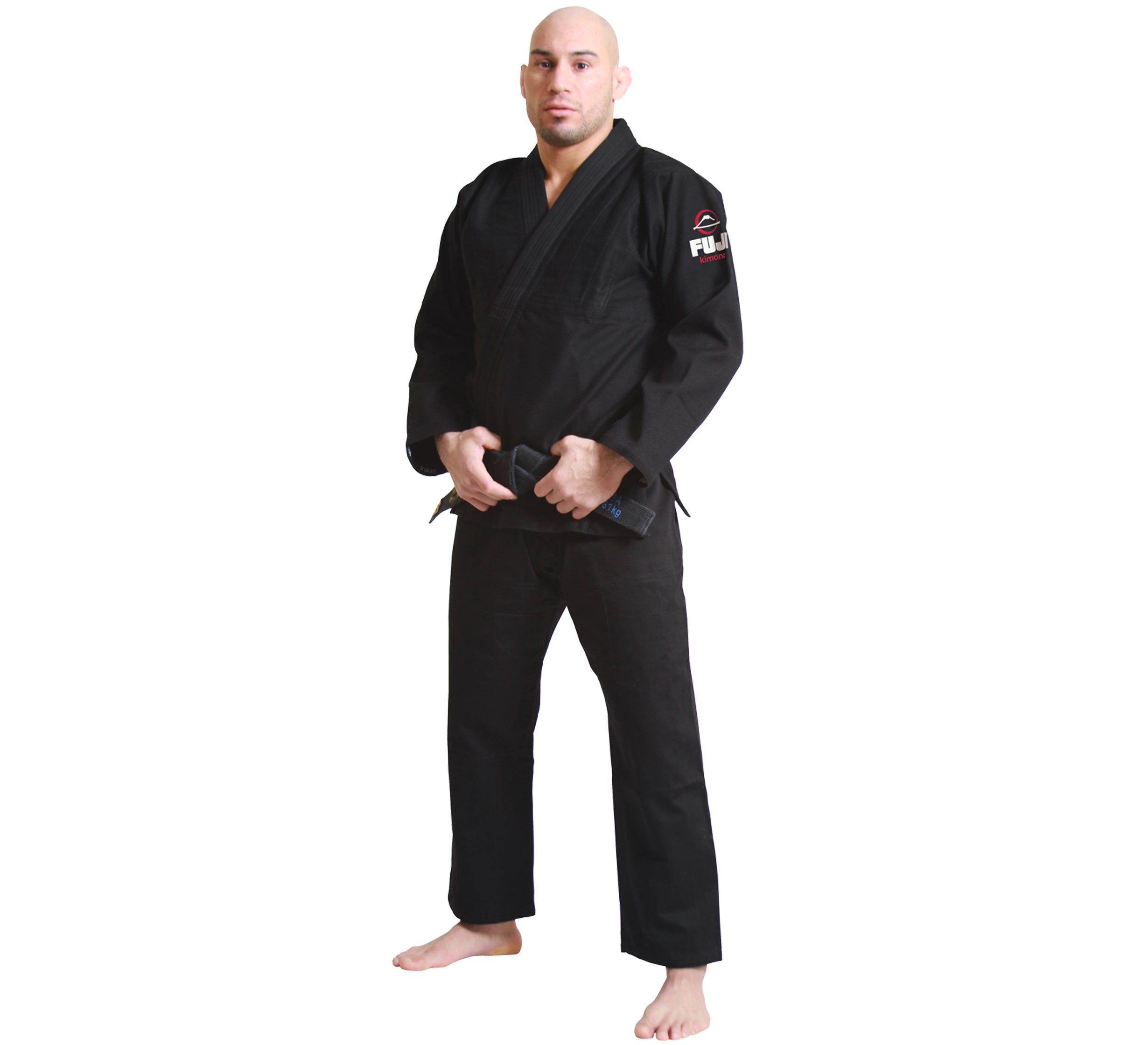 A man stands barefoot on a white background, wearing the All Around BJJ Gi Black and holding a black belt in front of him.
